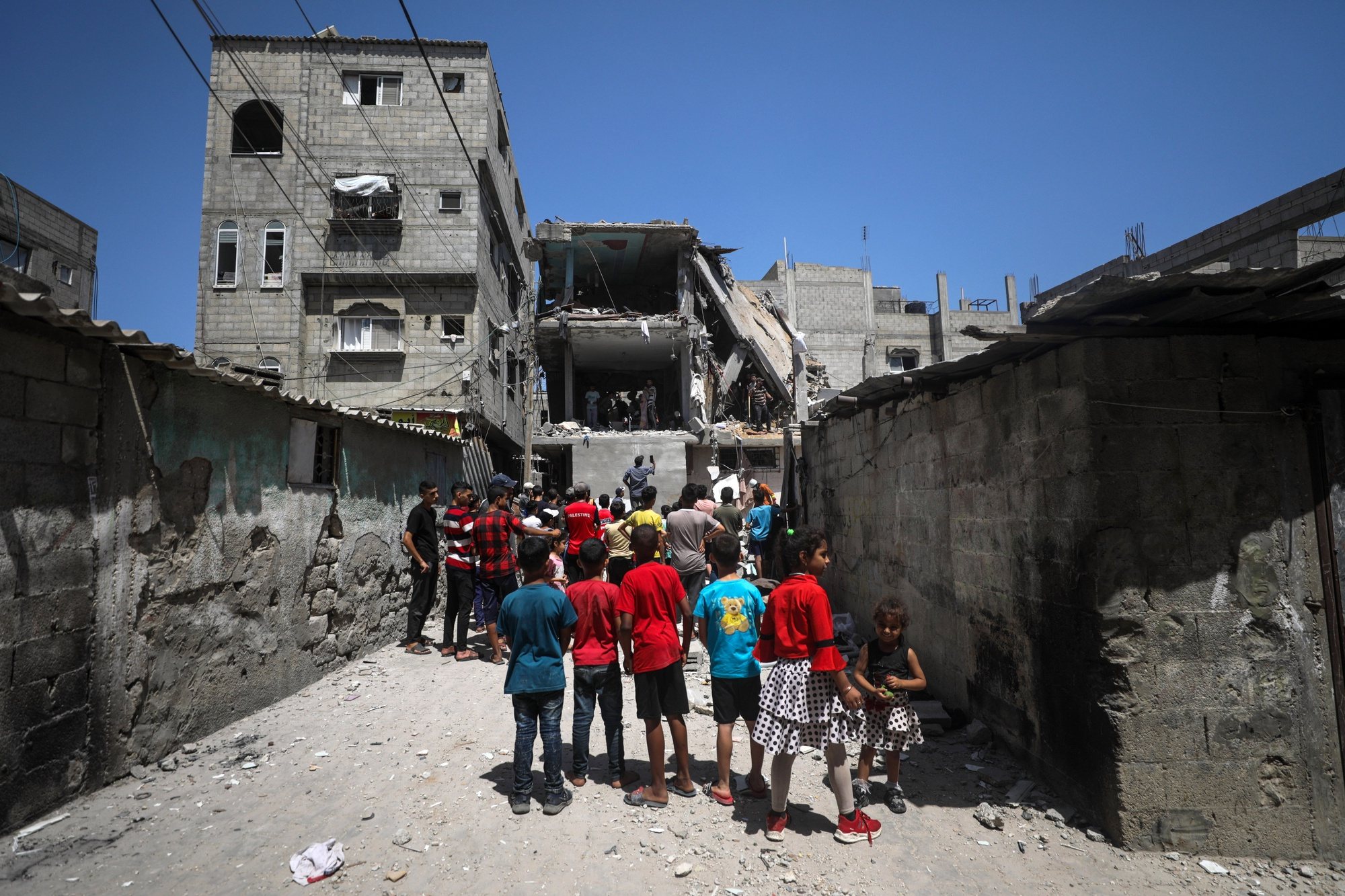 epa11419506 Palestinian children look at Civil Defense officers and civilians searching for missing people under the rubble of a destroyed house following an Israeli air strike, at al-Nuseirat refugee camp, southern Gaza Strip, 18 June 2024. More than 37,000 Palestinians and over 1,400 Israelis have been killed, according to the Palestinian Health Ministry and the Israel Defense Forces (IDF), since Hamas militants launched an attack against Israel from the Gaza Strip on 07 October 2023, and the Israeli operations in Gaza and the West Bank which followed it.  EPA/MOHAMMED SABER