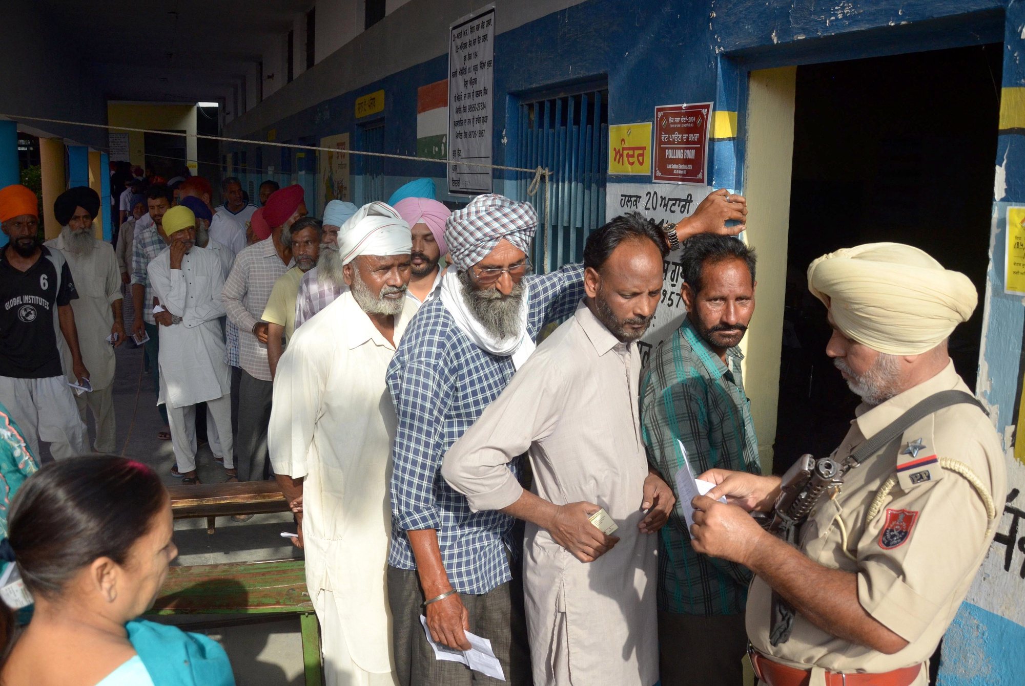 epa11383132 Indian voters have their ID papers checked by an armed security officer as they queue during the seventh and last phase of the Indian parliament elections outside a polling station on the outskirts of Amritsar, Punjab, India, 01 June 2024. General elections in India are held over seven phases between 19 April and 01 June 2024, which are held every five years and about 968 million people are eligible to vote. Results will be announced on 04 June 2024 for India&#039;s 545-member lower house of parliament, or Lok Sabha.  EPA/MANU ARORA