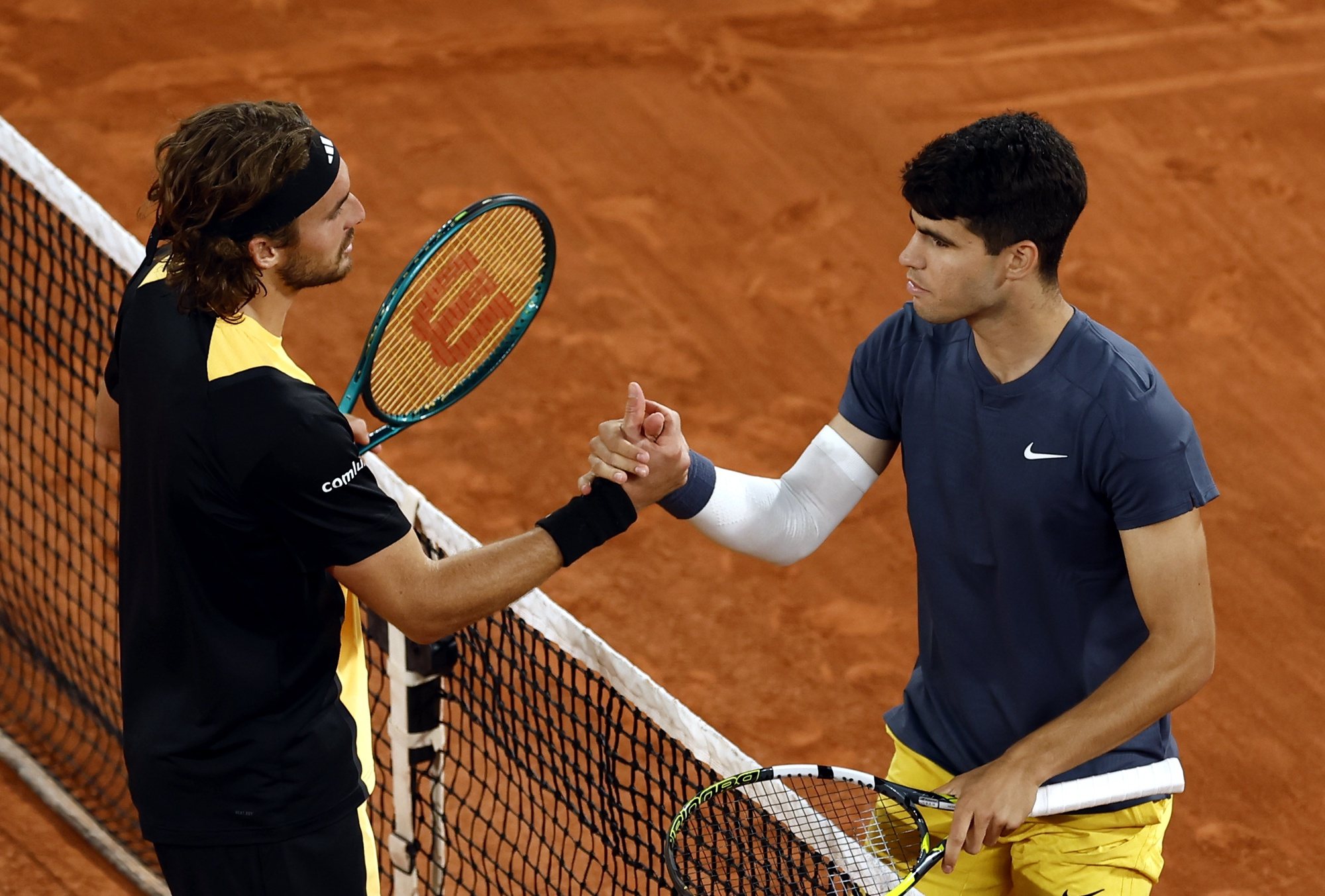epa11390152 Carlos Alcaraz of Spain (R) shakes hands with Stefanos Tsitsipas of Greece after winning his Men&#039;s Singles quarterfinal match during the French Open Grand Slam tennis tournament at Roland Garros in Paris, France, 04 June 2024.  EPA/YOAN VALAT