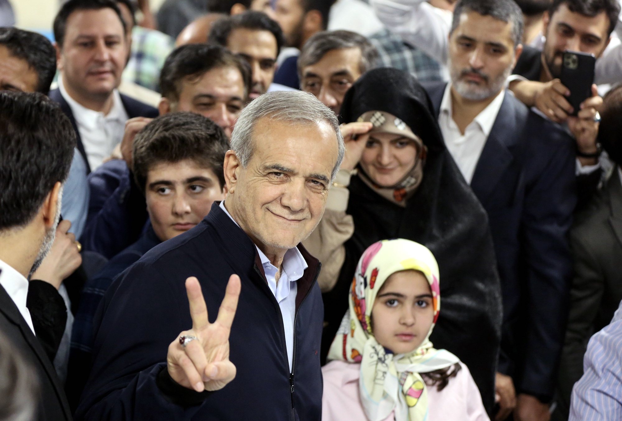 epaselect epa11442776 Iranian reformist presidential candidate Masoud Pezeshkian (C) flashes a victory sign as he arrives to cast his vote at a polling station during the presidential election in Tehran, Iran, 28 June 2024. Iran holds presidential elections on 28 June, following the death of late Iranian President Ebrahim Raisi in a helicopter crash on 19 May 2024.  EPA/STRINGER