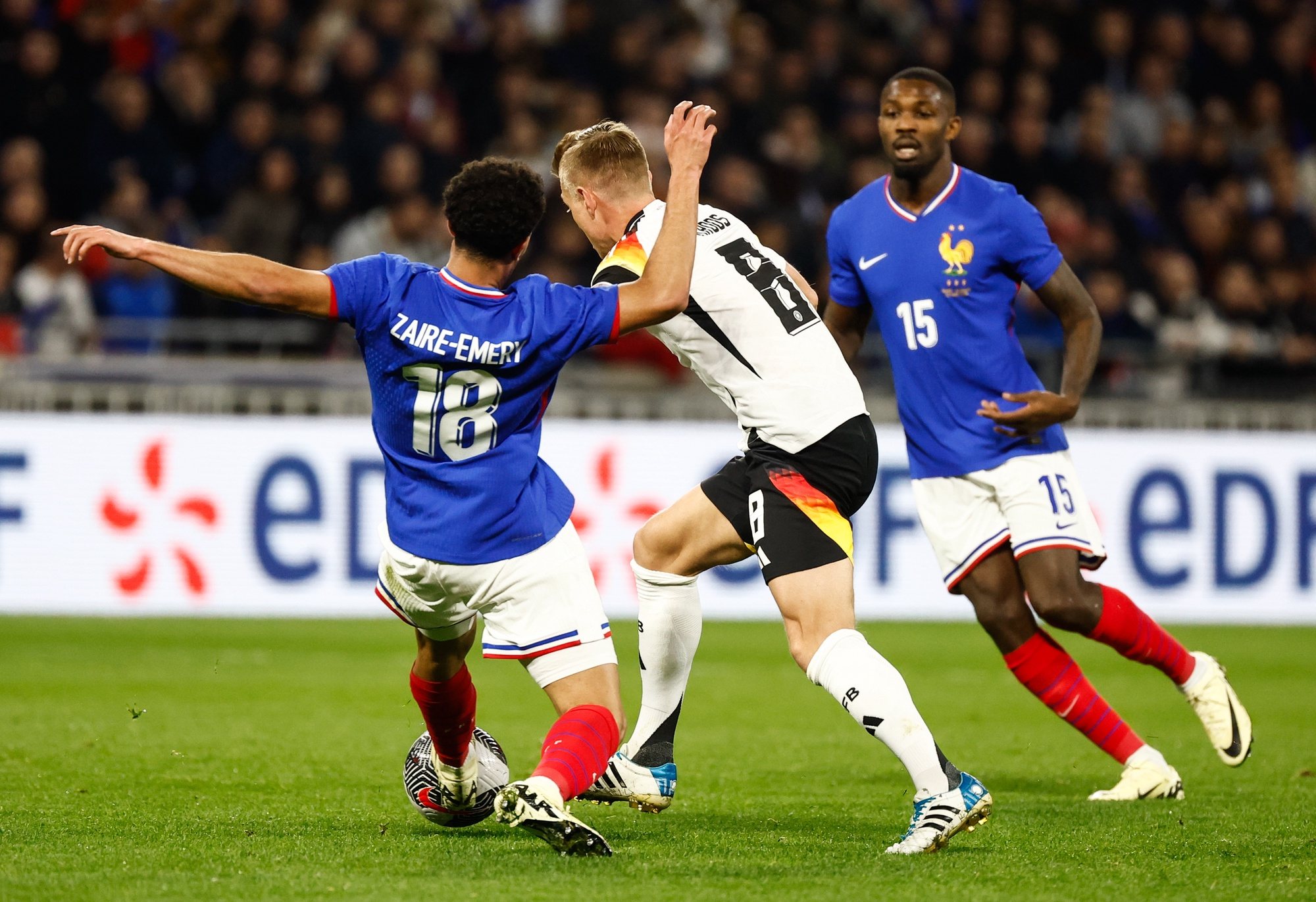 epa11239946 Toni Kroos (C) of Germany in action against Zaire Emry (L) and Marcus Thuram (R) of France during the friendly international soccer match between France and Germany, in Decines-Charpieu, near Lyon, France, 23 March 2024.  EPA/MOHAMMED BADRA