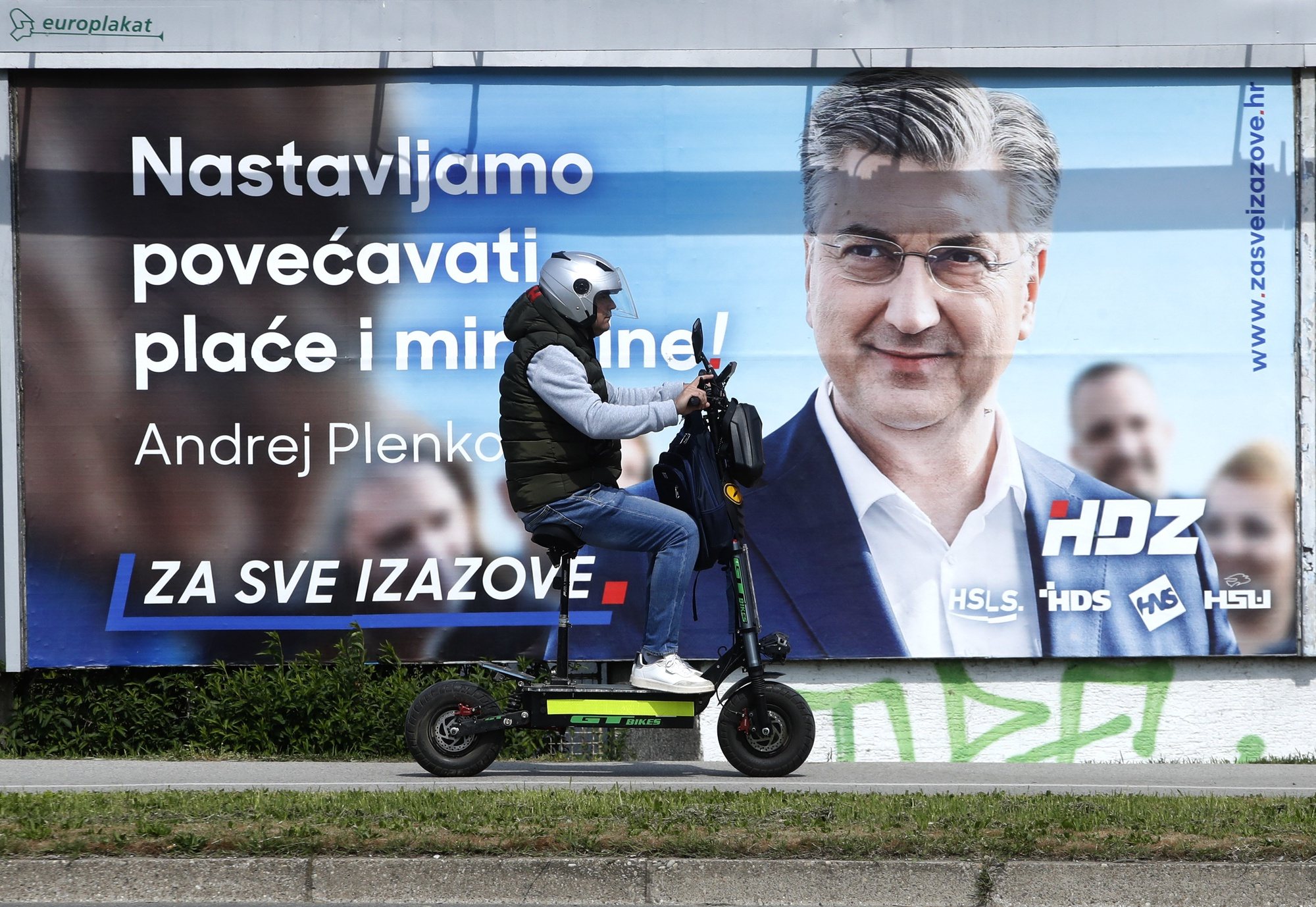 epa11278007 A man on scooter passes near posters of Croatian Democratic Union (HDZ) and Prime Minister Andrej Plenkovic poster reading &#039;We continue to increase salaries and pensions&#039; in Zagreb, Croatia, 14 April 2024. Croatian people will vote in parliamentary elections on 17 April 2024.  EPA/ANTONIO BAT
