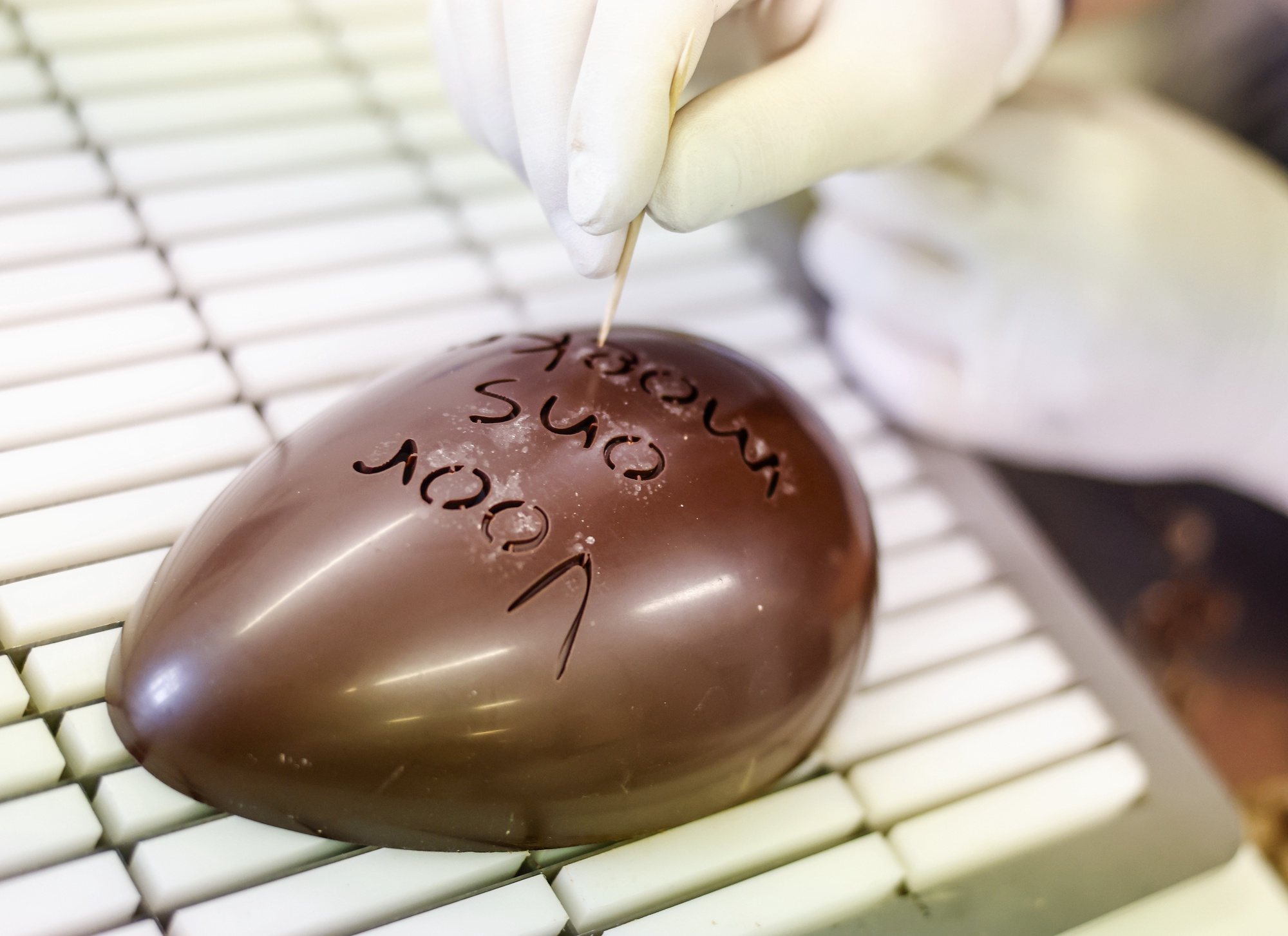epa11247017 An employee works on an Easter egg at the chocolate factory &#039;Confiserie Felicitas&#039; in Hornow near Spremberg, Germany, 27 March 2024. The Confiserie Felicitas is a family company run by a Belgian couple who settled in Germany in the early 1990s with the idea to produce good chocolate based on a Belgian recipe. The weeks before Easter are the most important time of the year for the chocolates industry.  EPA/HANNIBAL HANSCHKE