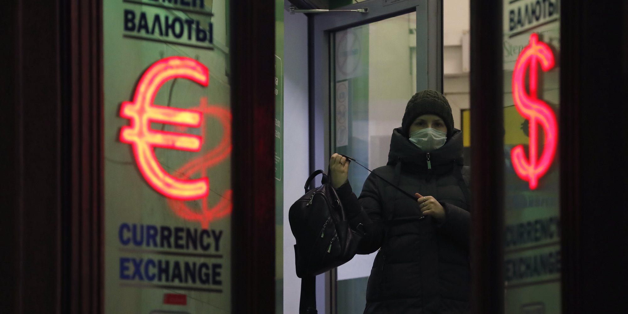 epa09785377 A woman exits between light panels displaying the euro and dollar signs at an exchange office in St. Petersburg, Russia, 25 February 2022. The dollar and the euro are confidently rising on the Moscow and St. Petersburg Exchanges, the ruble accelerated its fall against the dual-currency basket in anticipation of the announcement by Western countries of the previously announced new anti-Russian sanctions. In response to the military operation of the Russian armed forces that began in Ukraine, US authorities imposed sanctions against a number of key Russian banks. The US sanctions list includes VTB, Sberbank, Gazprombank, Sovcombank, Novikombank, Otkritie Bank, Alfa-Bank and Credit Bank of Moscow.  EPA/ANATOLY MALTSEV