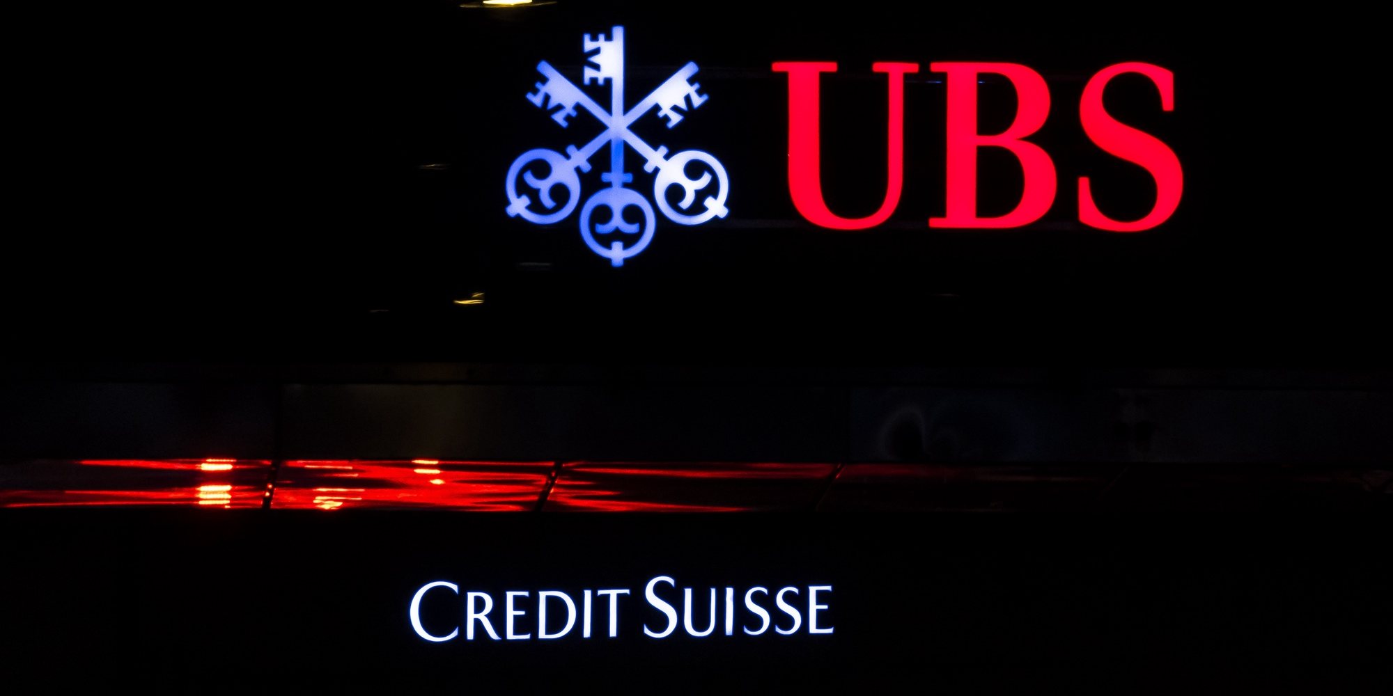 epa10529298 The illuminated logos of the Swiss banks Credit Suisse and UBS are displayed on buildings in Zurich, Switzerland, 18 March 2023. Shares of Credit Suisse lost more than one-quarter of their value on 15 March, hitting a record low after its biggest shareholder, the Saudi National Bank, told outlets that it would not inject more money into the ailing Swiss bank.  EPA/MICHAEL BUHOLZER