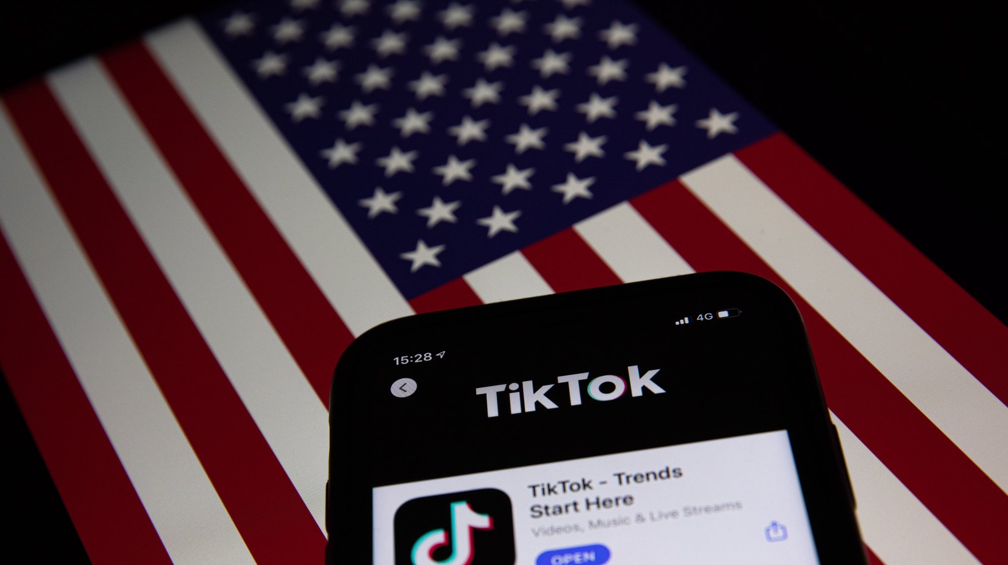 epa08685860 A generic illustration shows the icon of Chinese internet media app TikTok on a phone, and the US flag on a laptop screen, in Beijing, China, 21 September 2020. Chinese-owned mobile app WeChat was set to stop operation in the U.S. on midnight 20 September 2020.  EPA/ROMAN PILIPEY