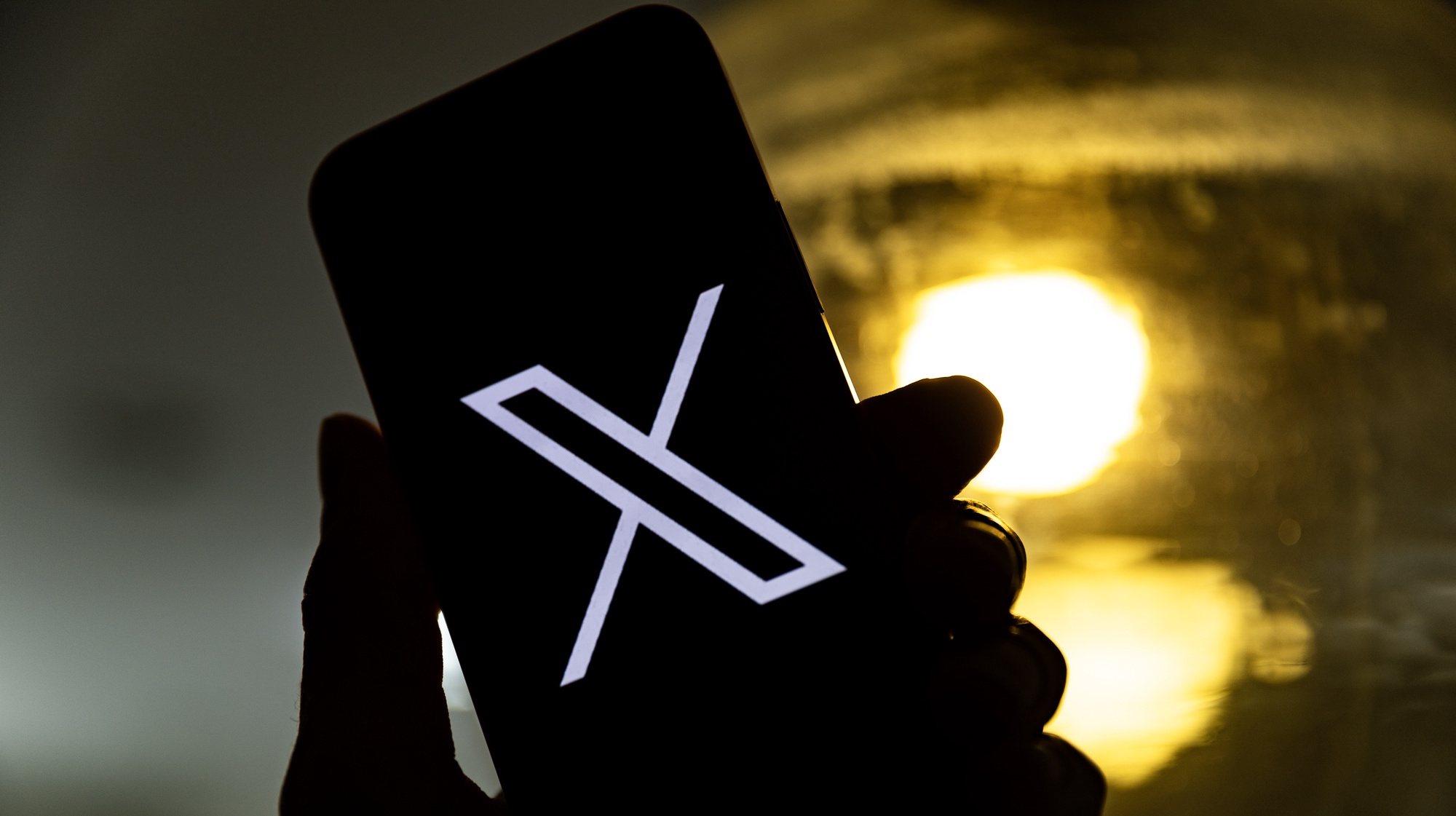 epa10772440 An illustration pictures shows a user holding a mobile phone displaying the &#039;X&#039; logo, in Los Angeles, California, USA, 27 July 2023. Twitter announced on 23 July that it will rebrand to X.  EPA/ETIENNE LAURENT
