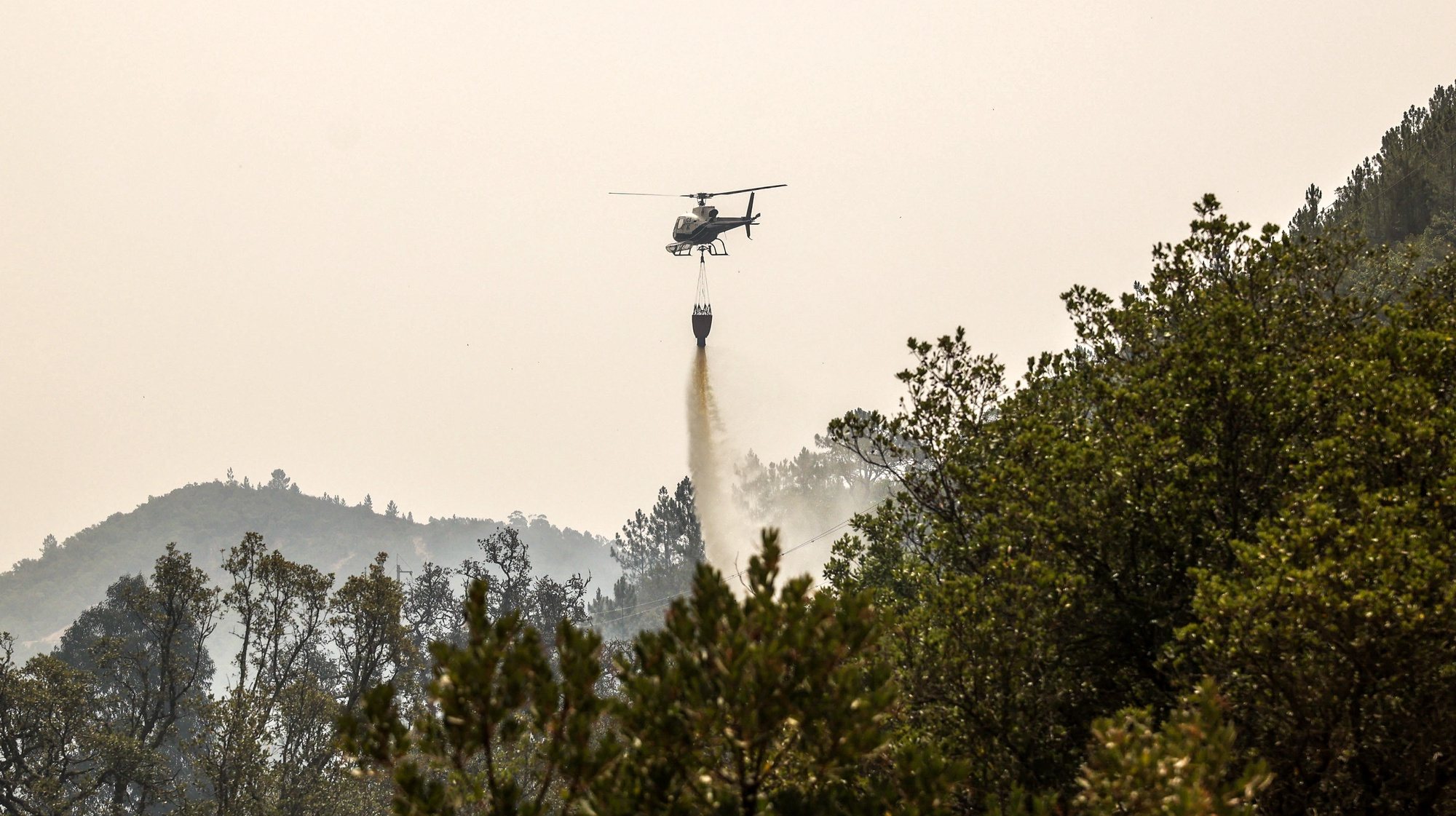 Um helicóptero combate um incêndio na zona de Galé de Cima no concelho de Aljezur, 9 de agosto de 2023. O incêndio rural que deflagrou no sábado em Odemira e entrou nos concelhos de Monchique e Aljezur (Faro) destruiu pelo menos duas casas e uma unidade de turismo rural, além de vários anexos.  MIGUEL A. LOPES/LUSA