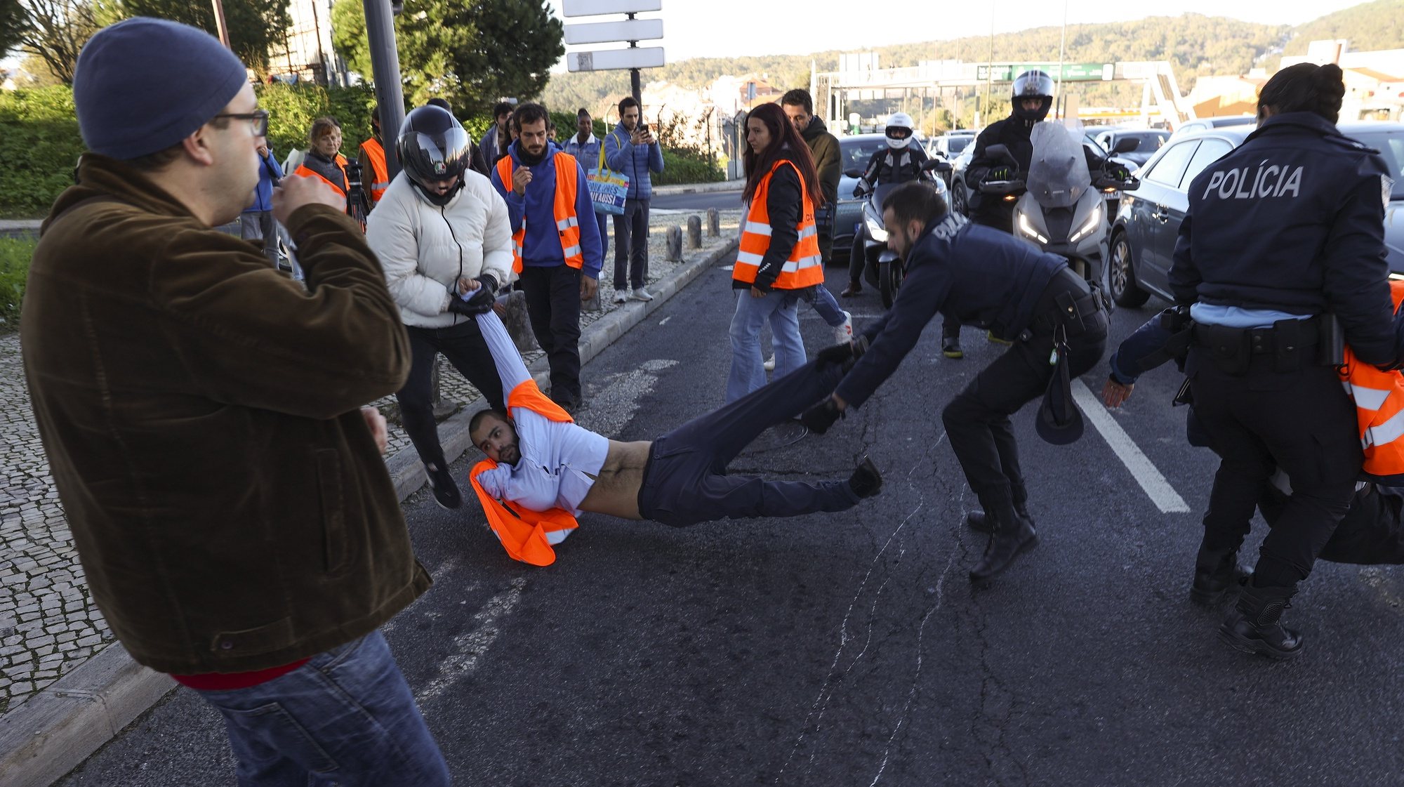 Agentes da Polícia e populares retiram ativistas da Climáximo que bloqueiam o acesso a Lisboa pela A5 durante uma ação de protesto, 14 de dezembro de 2023. MIGUEL A. LOPES/LUSA