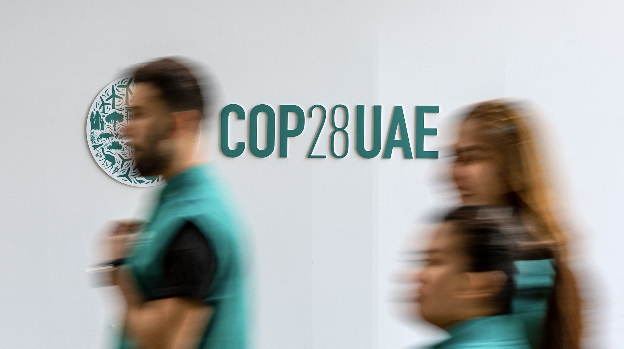 epa11022826 Participants walk past the COP28 logo at Expo Dubai, the venue of the 2023 United Nations Climate Change Conference (COP28), in Dubai, United Arab Emirates, 11 December 2023. COP28 runs from 30 November to 12 December, and is expected to host one of the largest number of participants in the annual global climate conference as over 70,000 estimated attendees, including the member states of the UN Framework Convention on Climate Change (UNFCCC), business leaders, young people, climate scientists, Indigenous Peoples and other relevant stakeholders will attend.  EPA/MARTIN DIVISEK