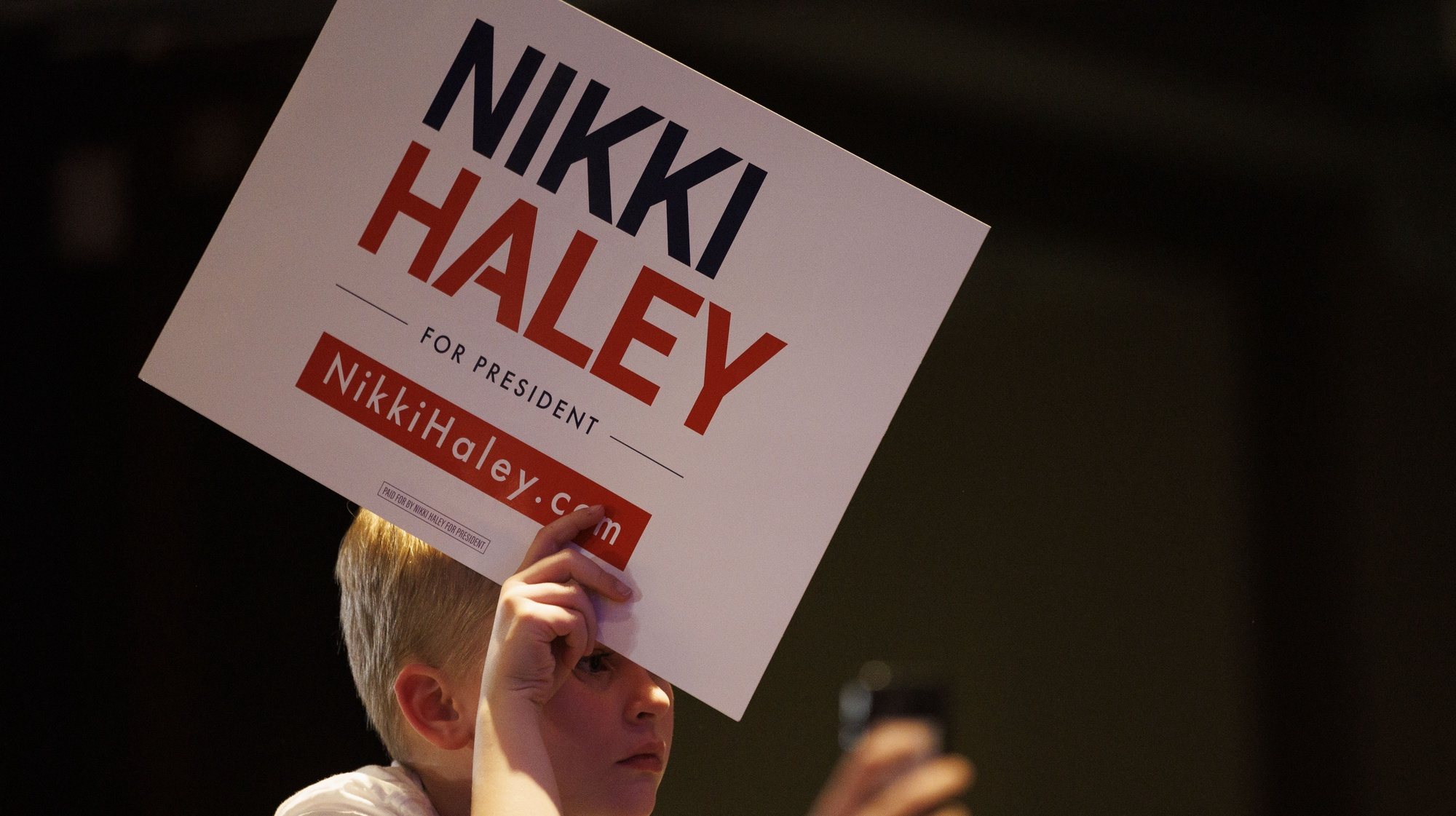 epa11195674 A young boy holds a campaign placard as he listens to Republican US presidential candidate Nikki Haley during a campaign stop in Needham, Massachusetts, USA, 02 March 2024. The former South Carolina governor Haley is running against former US President Donald Trump ahead of the &#039;Super Tuesday&#039; Republican primaries 05 March 2024.  EPA/CJ GUNTHER