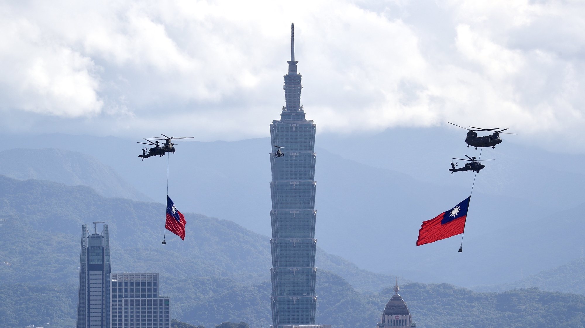 epaselect epa09510327 Chinook helicopter accompanied by Apache combat helocopters hoist giant Taiwan flags as they fly near the &#039;Taipei 101&#039; tower in downtown Taipei during a Taiwan flag flyby rehearsal ahead of the country&#039;s National Day in Taipei, Taiwan, 07 October 2021. The 12x18 meters Taiwan flag will be the largest ever used in a the National Day flag flyby on 10 October. President Tsai Ing-wen said on 05 October that Taiwan is committed to defend itself if its democracy is threatened following the incursion of 52 Chinese People&#039;s Liberation Army (PLA) military aircrafts into Taiwan&#039;s air defense identification zone (ADIZ) earlier this week.  EPA/RITCHIE B. TONGO