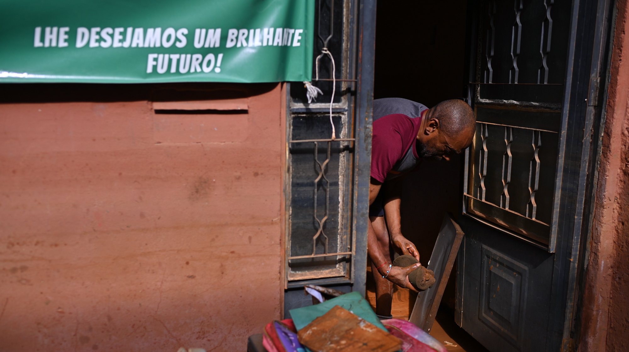 epa11348630 A resident works on cleaning his house in an area where flood water levels have already receded in the Menino Deus neighborhood, in Porto Alegre, state of Rio Grande do Sul, Brazil 17 May 2024. The waters of the Guaiba River began to drop slightly, two weeks after the start of the unprecedented flood that has since kept the Brazilian city of Porto Alegre flooded.  EPA/Andre Borges