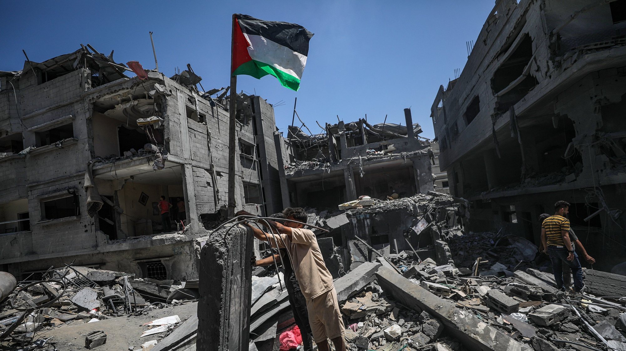 epaselect epa11419600 Palestinians raise a Palestinian flag next to their destroyed house following an Israeli air strike at al-Bureij refugee camp, southern Gaza Strip, 18 June 2024. More than 37,000 Palestinians and over 1,400 Israelis have been killed, according to the Palestinian Health Ministry and the Israel Defense Forces (IDF), since Hamas militants launched an attack against Israel from the Gaza Strip on 07 October 2023, and the Israeli operations in Gaza and the West Bank which followed it.  EPA/MOHAMMED SABER