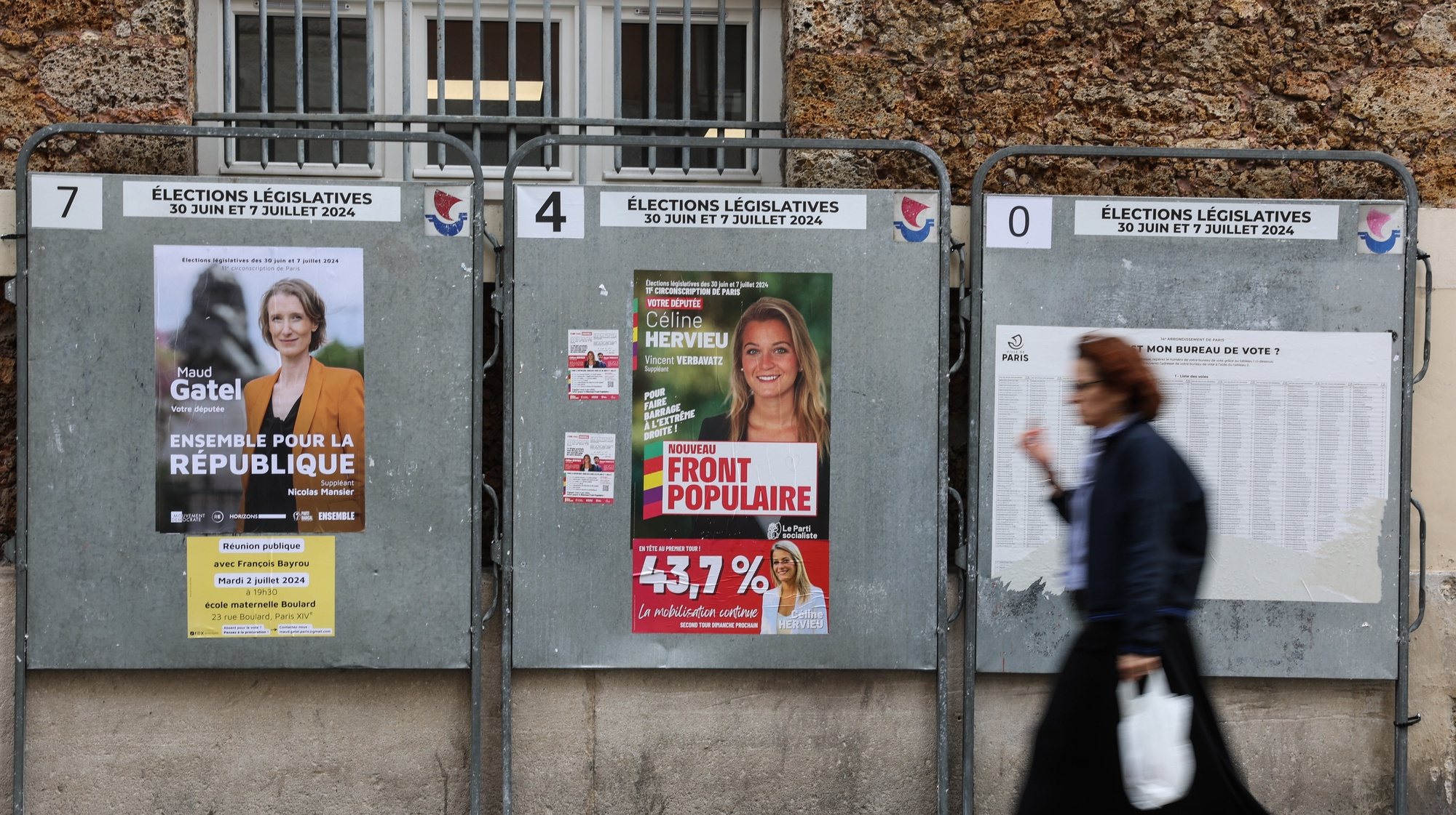 epa11456703 A woman walks past a poster for Nouveau Front Populaire &#039;The New Popular Front&#039;  candidates (C) for the parliamentary elections in Paris, France, 04 July 2024. The second round of the French parliamentary elections is to be held on 07 July 2024.  EPA/MOHAMMED BADRA