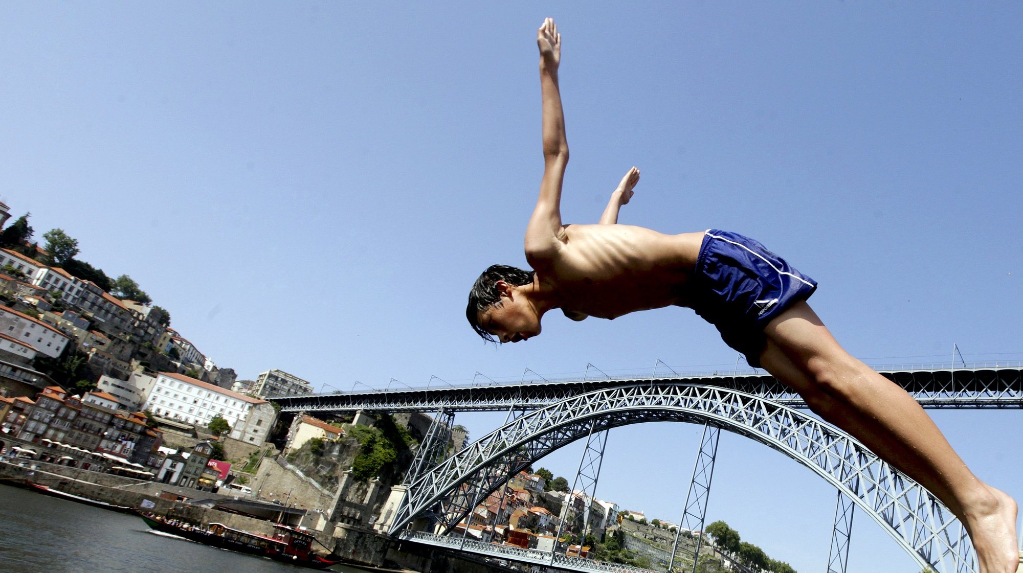 Um rapaz salta para o rio Douro no Porto, 31 de maio de 2012. Temperaturas elevadas na cidade do Porto levaram crianças a tomar banho no rio Douro. JOSE COELHO / LUSA