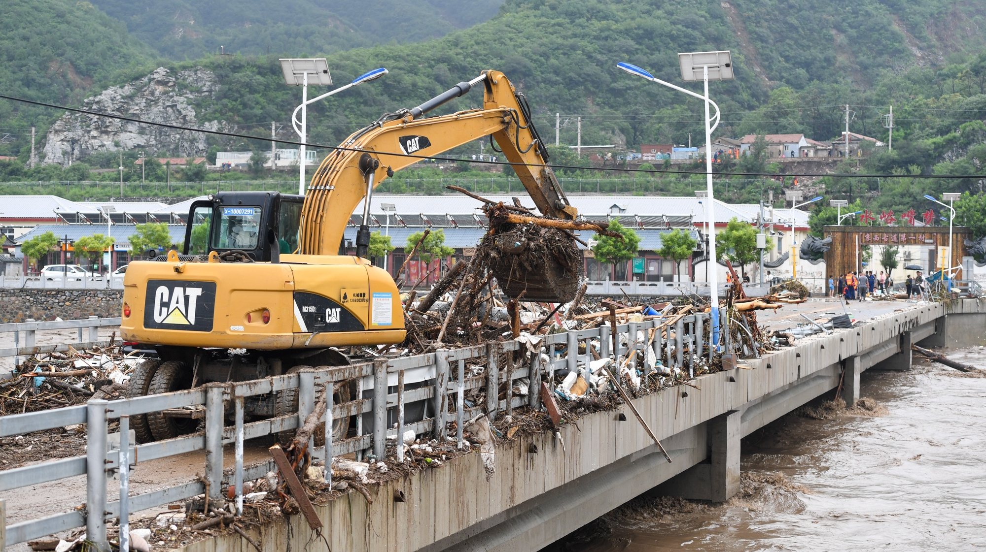 epa10780188 An excavator removes debris from a bridge at the Shuiyuzui Village in the flood-hit Mentougou District, Beijing, China, 01 August 2023. Several districts in the city, including the hardest-hit Fangshan and Mentougou, maintained the highest-level alert for flood control on 01 August, as downpours were expected to continue, the city&#039;s flood control authorities said.  EPA/XINHUA / Ju Huanzong CHINA OUT / MANDATORY CREDIT  EDITORIAL USE ONLY