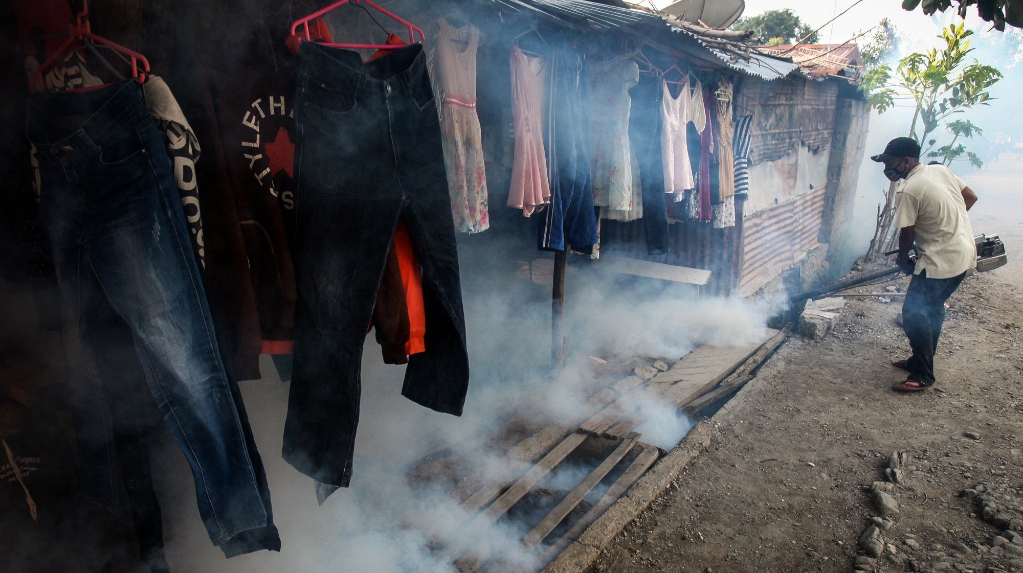 Um profissional de saúde de Timor colocar spray numa área residencial para prevenir infeções de dengue