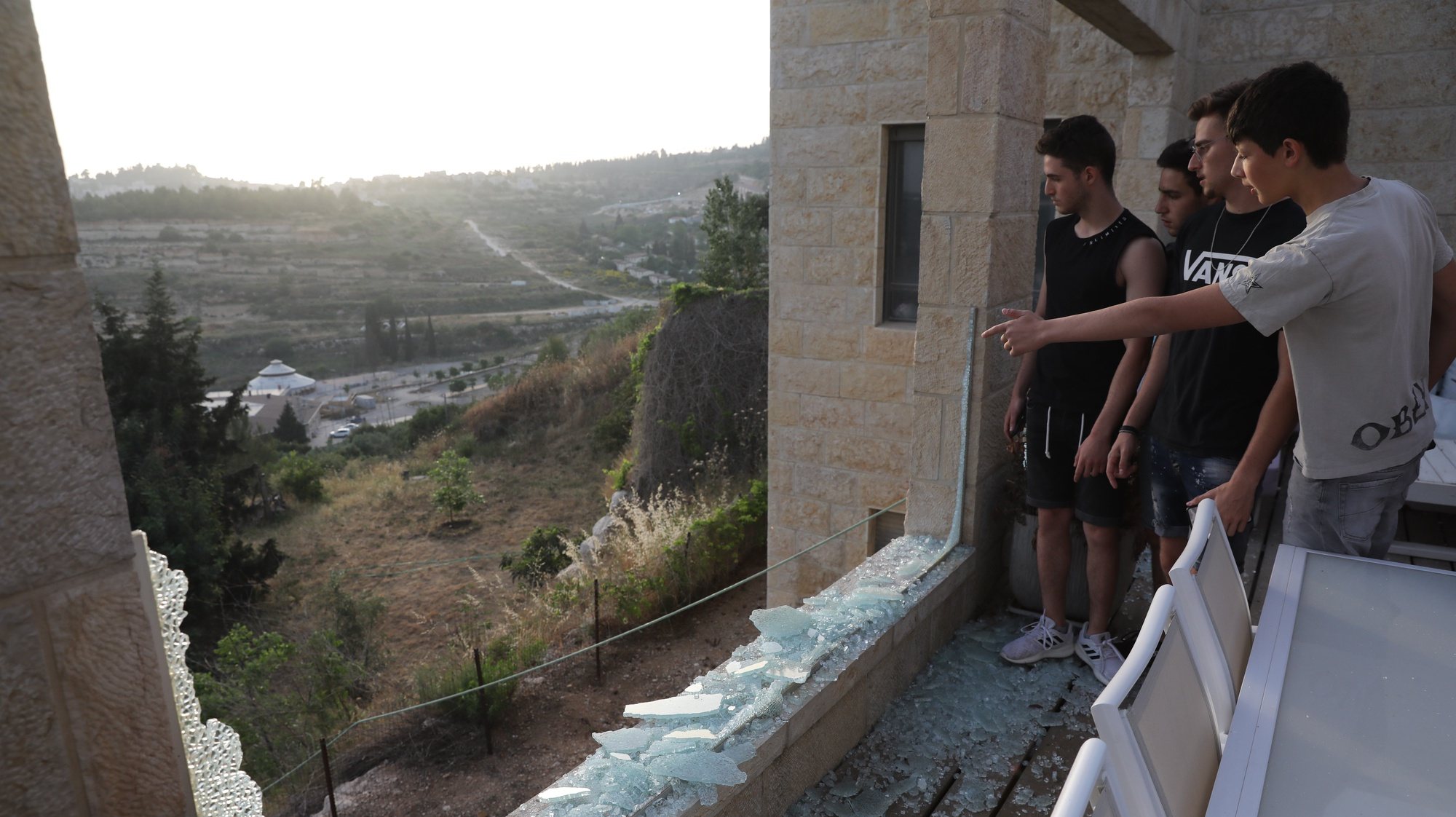 epa09189820 Israelis look out from a broken window in their home, as a result from missile fired from Gaza Strip, at the village of Beit Nekufa near Jerusalem, Israel, 10 May 2021 as tensions rise between Israel and Palestinians.  EPA/ABIR SULTAN