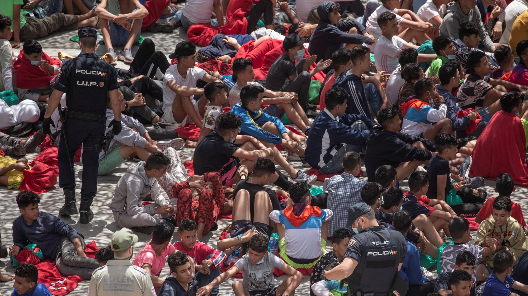 epa09218156 Migrants wait at an industrial estate next to Tarajal beach, in the city of Ceuta, Spanish enclave in northern Africa, 21 May 2021. Local authorities reported that between 8,000-10,000 migrants managed to enter Spain from 18 to 19 May.  EPA/BRAIS LORENZO ATTENTION EDITORS: FACES PIXELATED AT SOURCE DUE TO LEGAL REQUIREMENTS