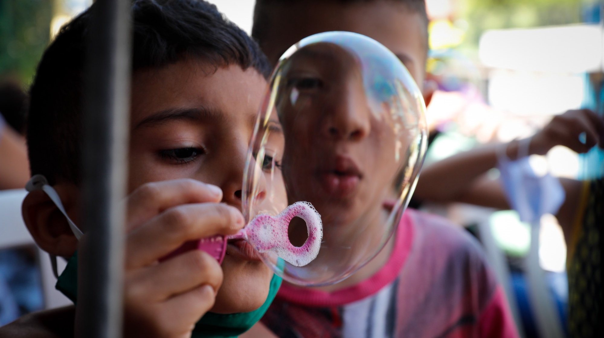 epa09100577 Children play with bubbles during a food donation delivery on 23 March 2021, in the Paraisopolis favela, on Paulista Avenue, in Sao Paulo, Brazil (Issued 27 March 2021). One year after the start of the pandemic, deaths and cases of covid-19 increase day by day in Brazil, but aid for the poorest does not stop falling. In Paraisopolis, one of the largest favelas in Sao Paulo, hunger hits the door of thousands of families hard.  EPA/Fernando Bizerra