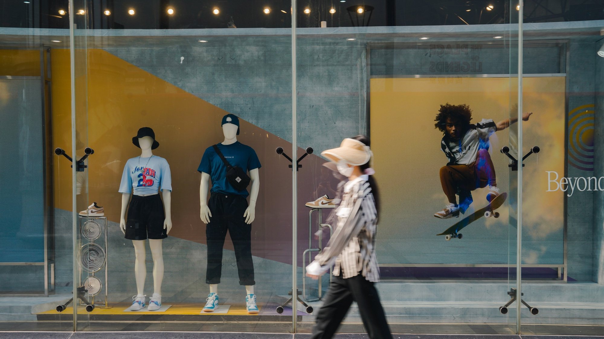 epa10790164 A woman walks by in front of the shop window of a clothing store in Beijing, China, 08 August 2023. China&#039;s trade surplus dropped to 80.6 billion US dollar (73.36 billion Euro) in July 2023, from 102.7 billion US dollar (93.47 billion euro) in the same period the prior year, as exports fell more than imports amid demand weakened from home and abroad, the General Administration of Customs reported.  EPA/WU HAO