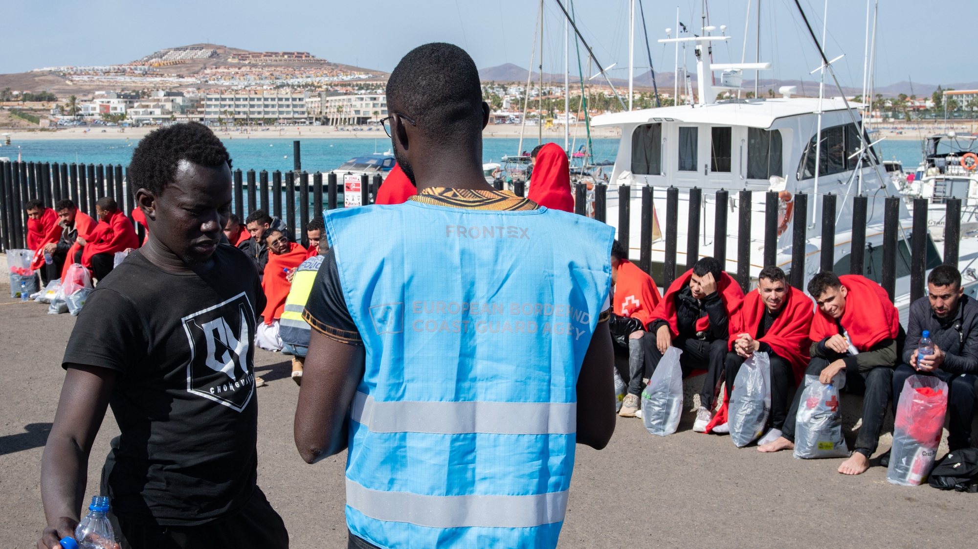 epa11123546 A migrant (L) talks to a Frontex worker upon the arrival of some 54 migrants in Caleta de Fuste, Fuerteventura island, Canary Islands, southwestern Spain, 03 February 2024.  EPA/Carlos de Saa