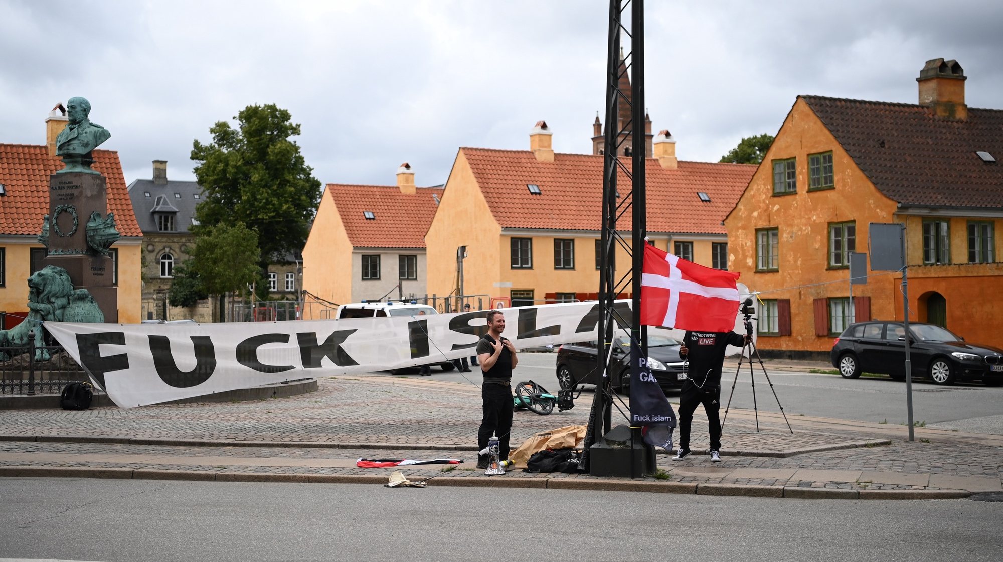 epa10766058 Two men from the far-right Danish group Danske Patrioter â€˜Danish Patriotsâ€™ hold a banner reading a message against Islam outside the Embassy of the Republic of Iraq in Copenhagen, Denmark, 24 July 2023. The two men set on fire a book they claim was a copy of the Koran and live-streamed it on the groupâ€™s social media. Danske Patrioter was responsible for burning another copy of the Koran in the same spot on 21 July, sparking a protest in Iraq the following day, with hundreds of protesters trying to storm the Green Zone in the Iraqi capital Baghdad.  EPA/Thomas Sjoerup DENMARK OUT