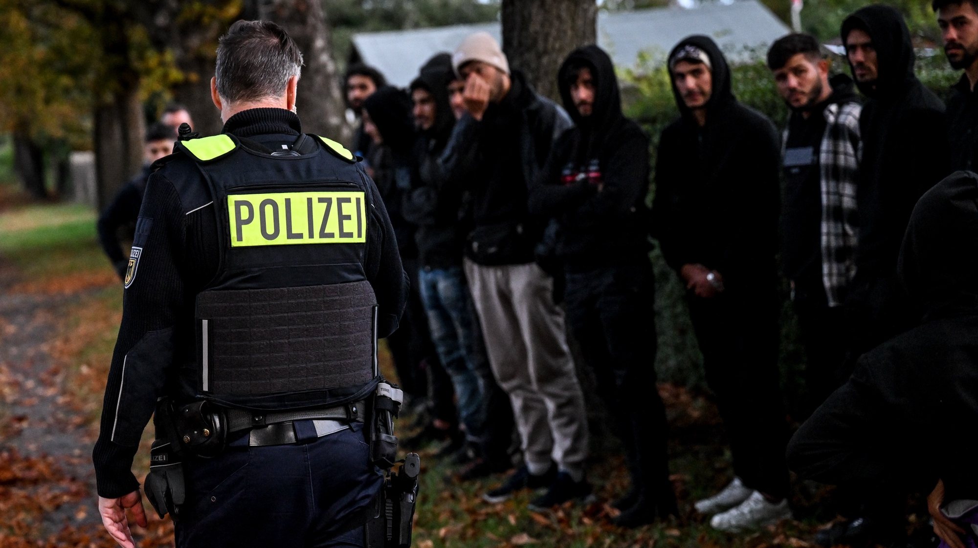 epa11040582 Migrants stand in line after being detained by German police during an operation to prevent illegal migration along the German-Polish border, near Frost, Germany, 11 October 2023. Due to the increasing number of refugees arriving in Germany via the Balkan and Mediterranean routes as well as war refugees from Ukraine, many refugee shelters in Germany have already reached their capacity limit.  EPA/FILIP SINGER