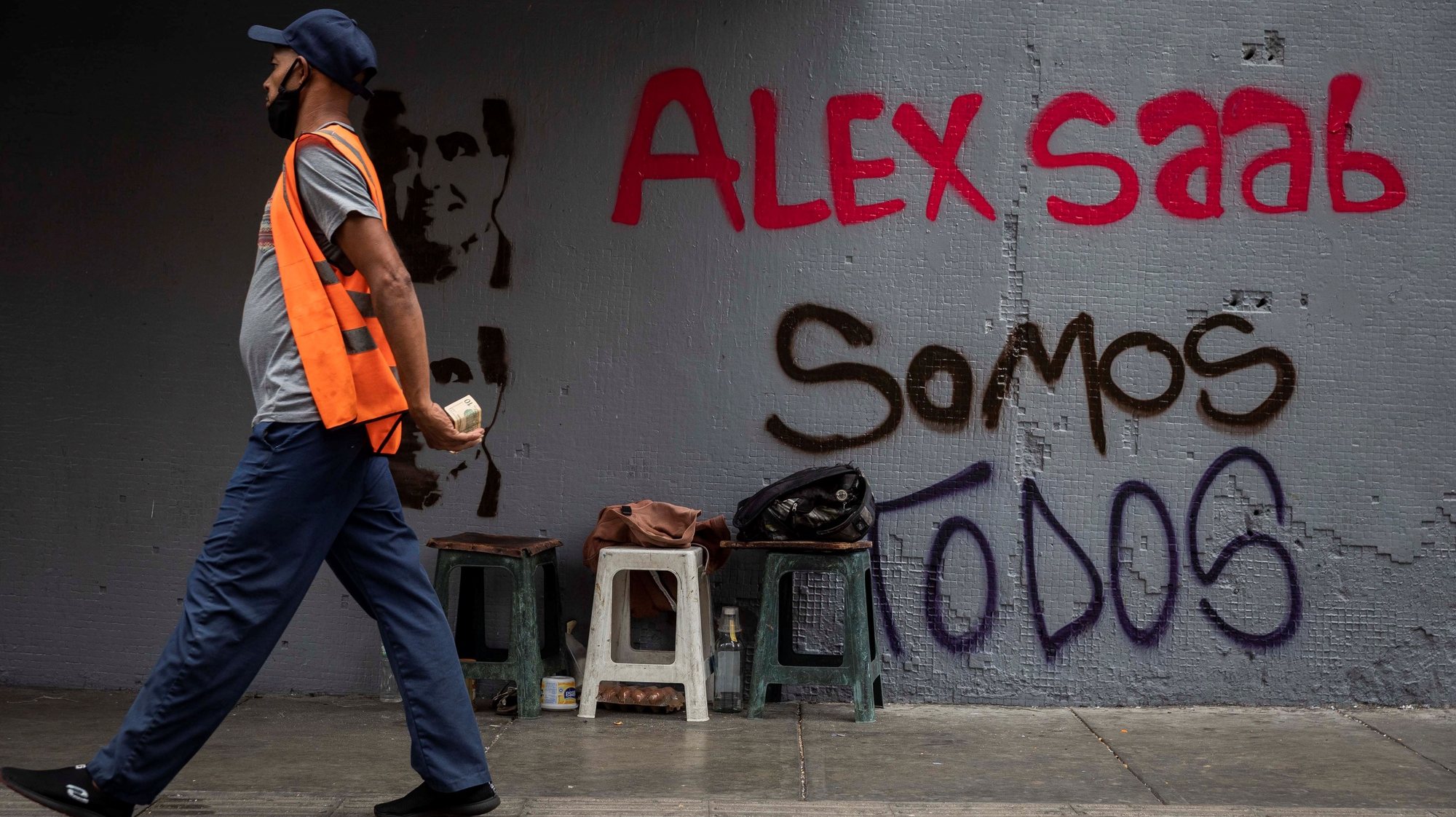 epa09030458 A man walks in front of a graffiti that reads &#039;We all are Alex Saab&#039;, in Caracas, Venezuela, 22 February 2021. Chavista supporters have painted murals in the Venezuelan capital to show their support and request the release of Alex Saab, a Colombian businessman detained in Cape Verde and whom the United States is asking for extradition by accusing him of being a front man for the president of Venezuela, Nicolas Maduro.  EPA/Rayner Pena