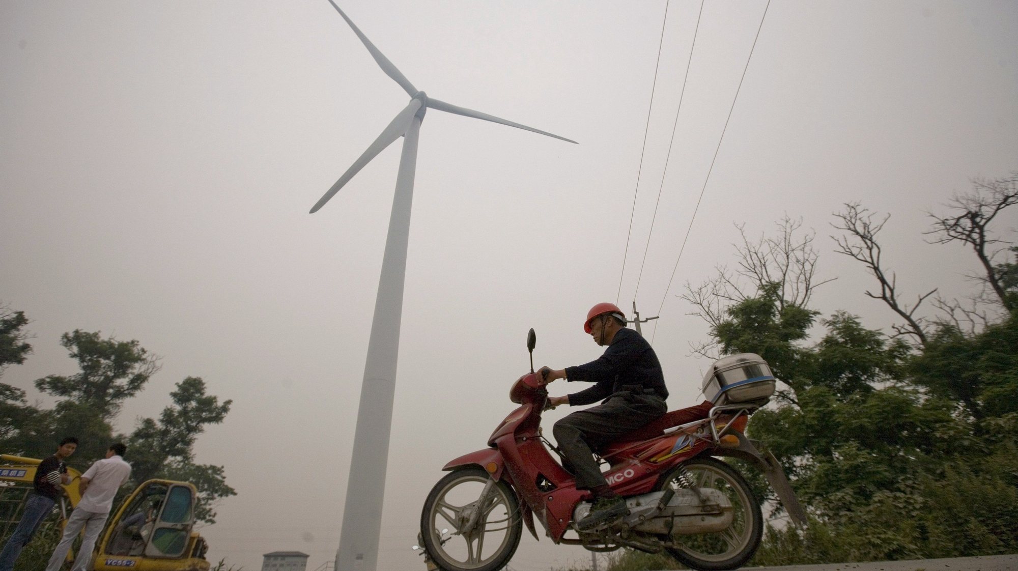 epa01749092 A man rides a motorcycle pass a large wind mill at the 100-megawatt Rudong wind farm, in Rudong city, China&#039;s Jiangsu province, 02 June 2009. Officials from China&#039;s National Energy Administration said today that China, currently the world&#039;s second-largest energy consumer behind the United States, will invest over 10 billion euro to increase the country&#039;s wind power capacity from 12,000 to 30,000 megawatts by 2010.  EPA/DIEGO AZUBEL