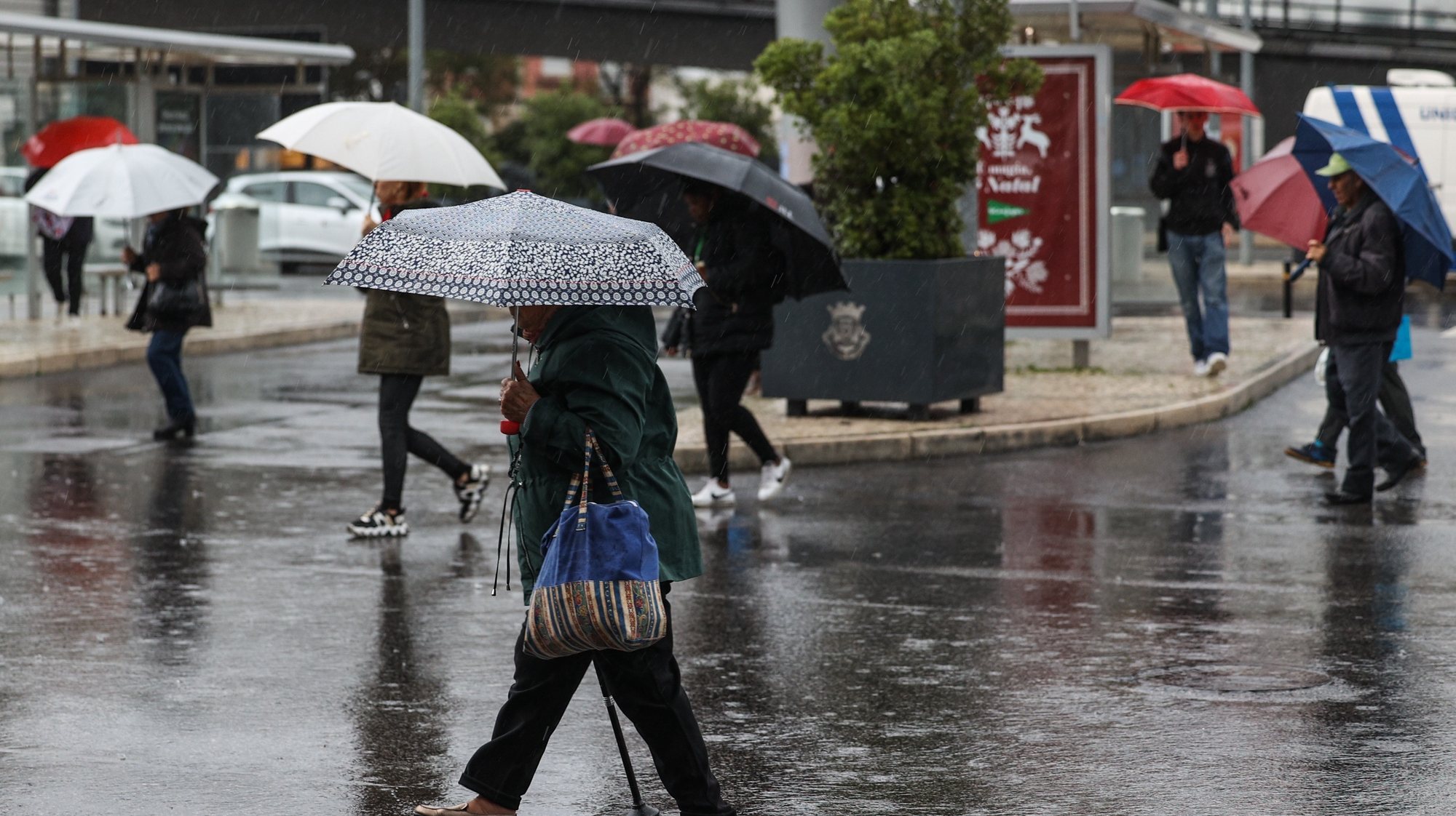 Traseuntes passam com chapéus de chuva na zona de Algés em Oeiras num dia de temporal, 14 de dezembro de 2022. TIAGO PETINGA/LUSA