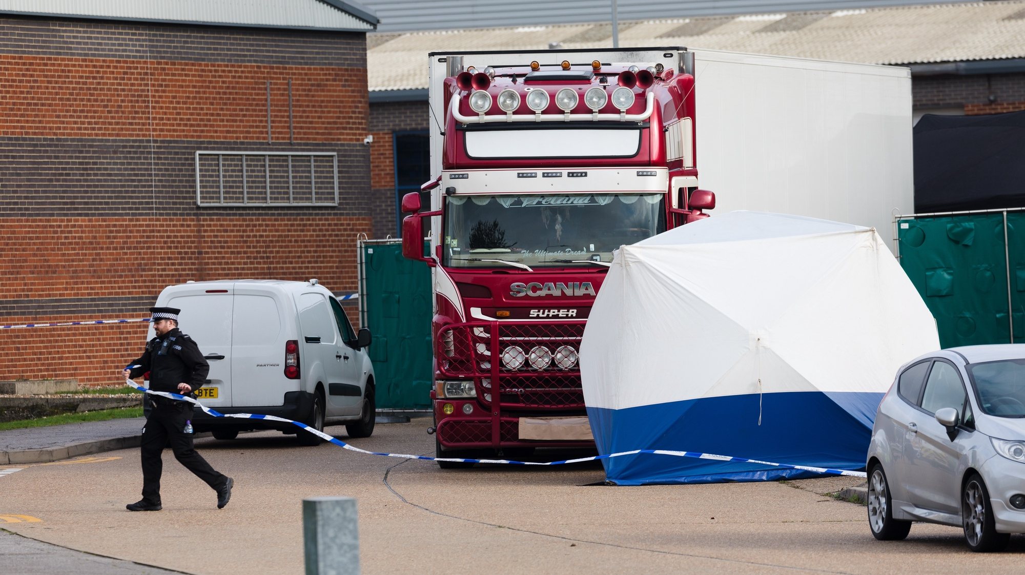 epa07943092 Police officers cordon off the area around the lorry at the scene in Waterglade Industrial Park in Grays, Essex, Britain, 23 October 2019. A total of 39 bodies were discovered inside a lorry container in the early hours of this morning, and pronounced dead at the scene.  EPA/VICKIE FLORES