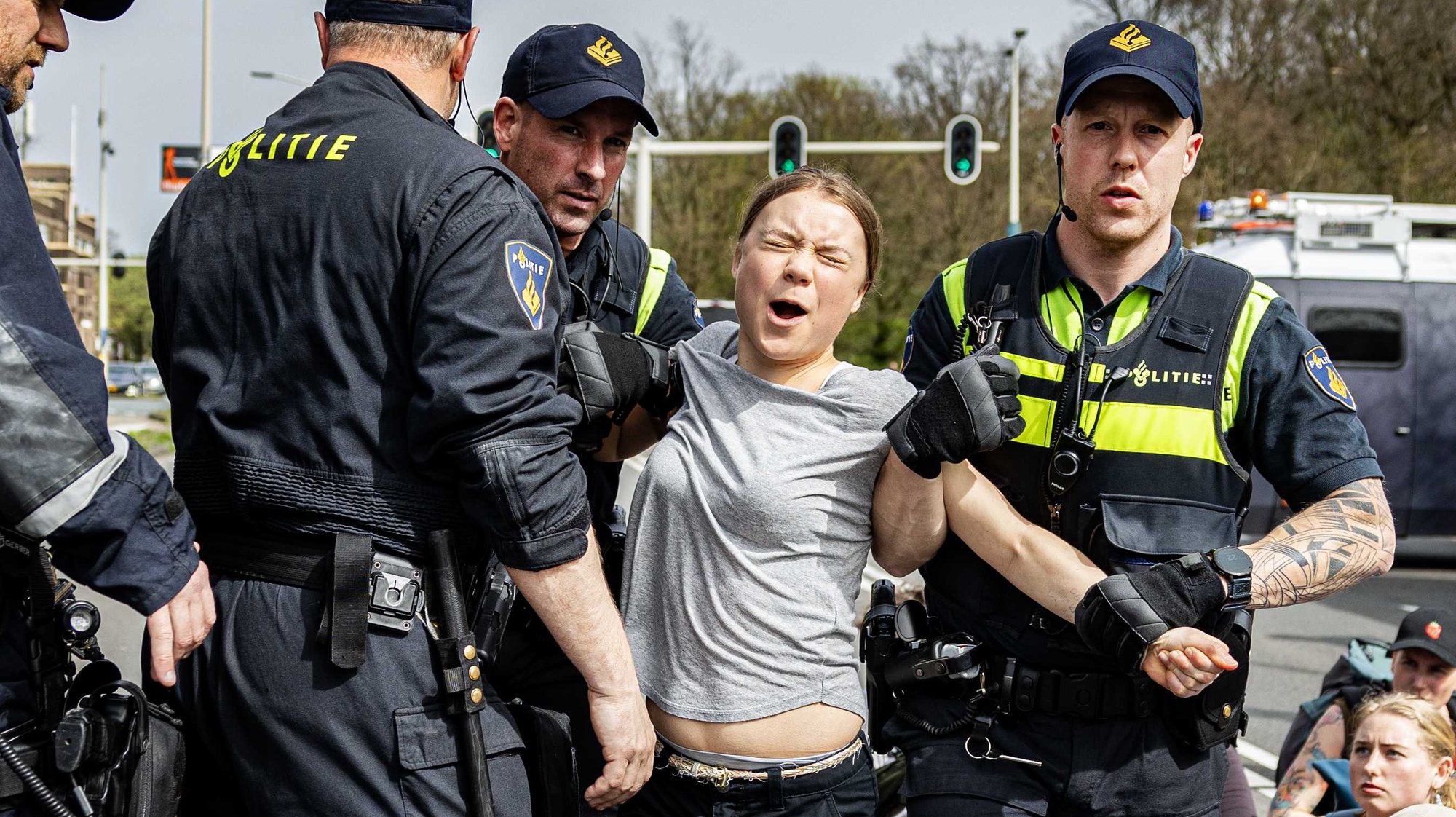 epa11262178 Swedish climate activist Greta Thunberg (2-R) reacts as she is detained by police officers during a climate demonstration blocking the A12 highway in the Hague, the Netherlands, 06 April 2024. Thunberg joined the 37th highway blockade called by the Extinction Rebellion as new international actions against fossil subsidies were announced during the action.  EPA/RAMON VAN FLYMEN