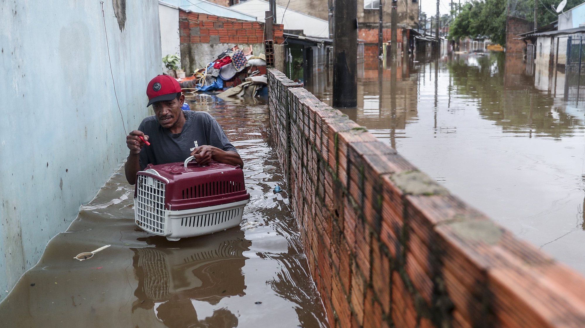 epa11336186 Wagner Souza leaves his flooded house with his cat Lilico in the Humaita neighborhood in Porto Alegre, Brazil, 12 May 2024. Boat rescues in the flooded neighborhoods of Porto Alegre in southern Brazil continue after authorities warned of a new rise in the Guaiba River in the coming days.  EPA/Sebastiao Moreira