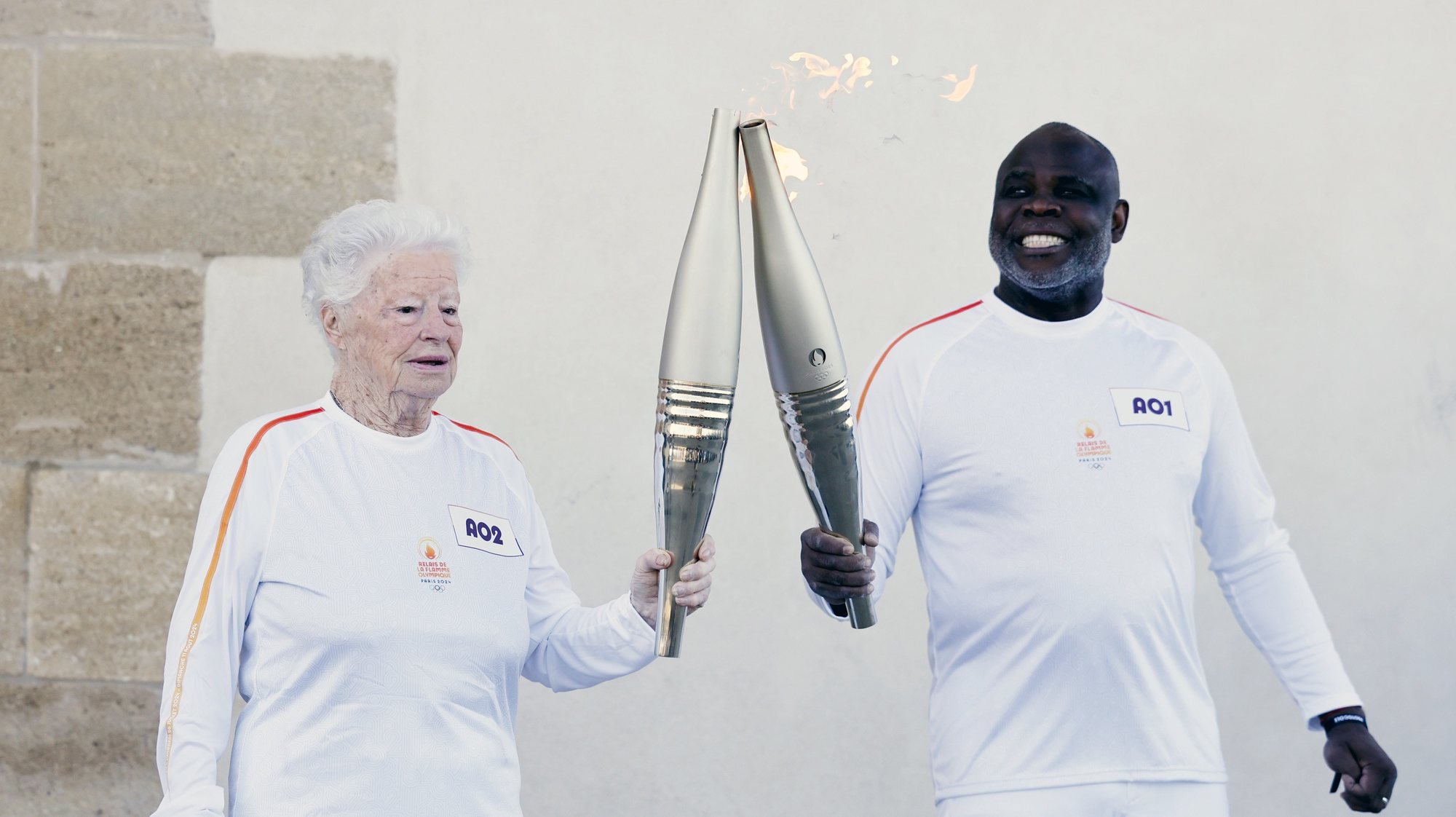 epa11328360 Former football player Basile Boli (R) gives the flame to Olympic Marseille&#039;s supporter Colette Cataldo during the first leg of Olympic Torch relay in Marseille, France, 09 May 2024. The Olympic Flame arrived in Marseille on 08 May following a 12-day journey from Piraeus, Greece, on board the Belem, a three-masted sailing ship built in 1896 and currently serving as a training ship under the French flag. The Paris 2024 Olympic Games will start on 26 July 2024.  EPA/GUILLAUME HORCAJUELO