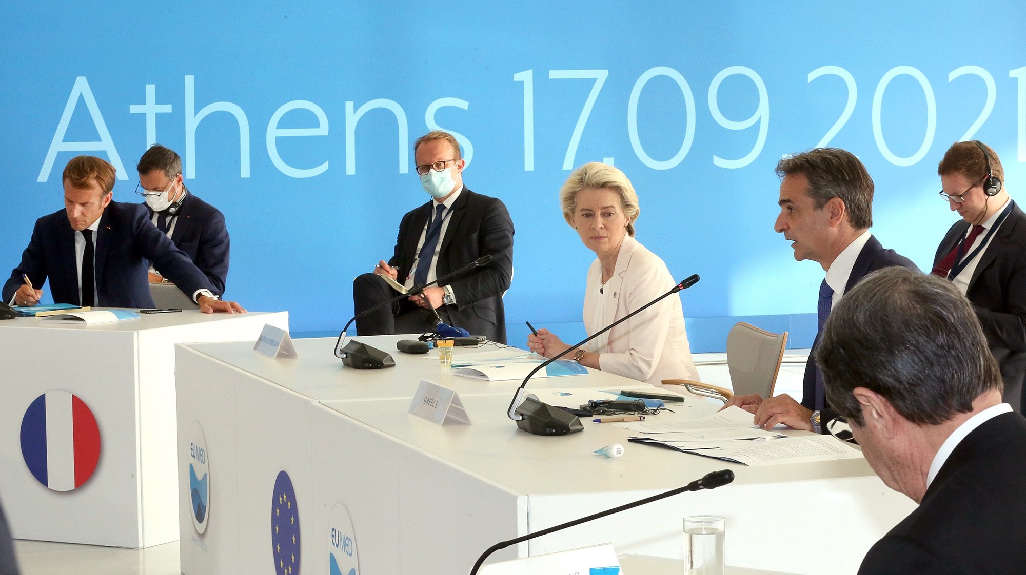 epa09473758 Greek Prime Minister Kyriakos Mitsotakis (R), President of the European Commission Ursula von der Leyen (R2) and French President Emmanuel Macron (L) participate at the EUMed9 Summit, in Athens, Greece, 17 September 2021.The agenda of the Summit, which acquires special geopolitical weight, includes security challenges in the Mediterranean that endanger stability in the region, potential new crises, such as the threat of migration flows after the latest developments in Afghanistan, and other crises, the consequences of which Mediterranean countries are already experiencing, such as climate change.  EPA/ORESTIS PANAGIOTOU