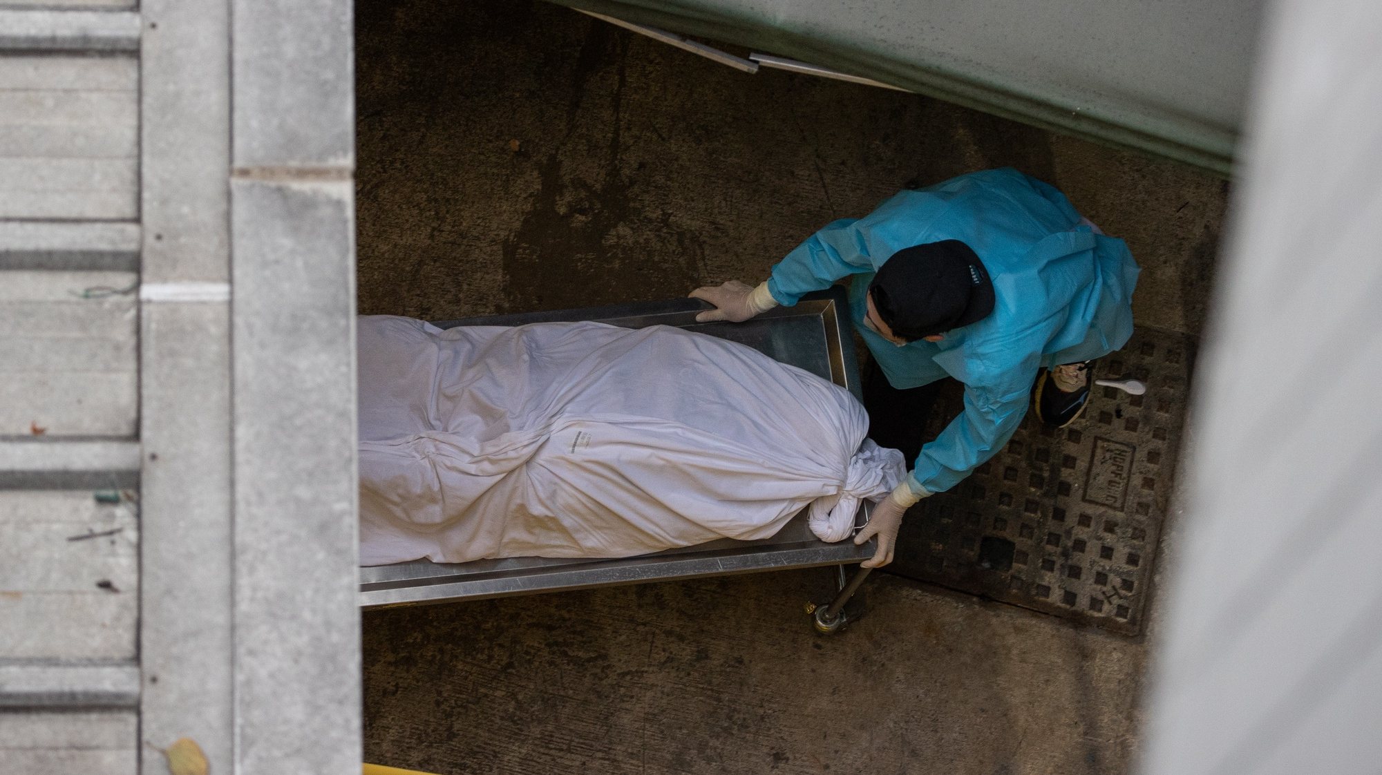 epa09796227 Funeral home staff load a dead body into a van outside the Caritas Medical Center in Hong Kong, China, 02 March 2022. Hong Kong health authorities said large freezer containers will be set up at public hospitals to store dead bodies as mortuaries are reaching capacity. A makeshift hospital is under construction in Hong Kong as the Omicron variant has brought the regionâ€™s public health system close to collapsing, with patients lying in beds placed outside health facilities.  EPA/JEROME FAVRE
