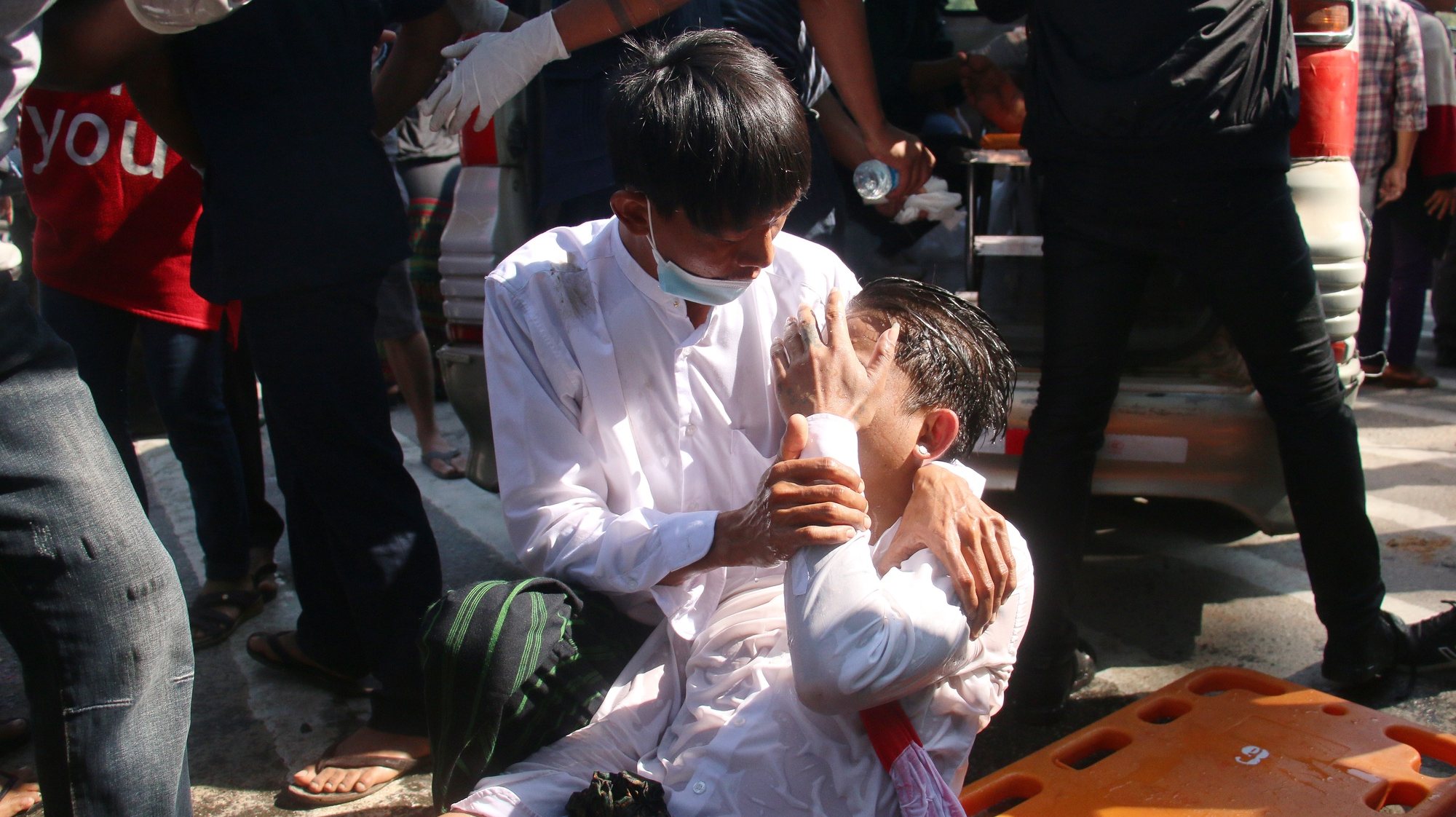 epa08997971 A man helps a demonstrator injured by police water cannons during a protest against the military coup, in Naypyitaw, Myanmar, 09 February 2021. Thousands of people continued to rally despite stern warnings from the military after days of mass protests. Orders were issued on 08 February in major cities and townships banning people from protesting or gathering in groups of more than five. A nighttime curfew was also imposed. Myanmar&#039;s military seized power and declared a state of emergency for one year after arresting State Counselor Aung San Suu Kyi, the country&#039;s president and other political figures in an early morning raid on 01 February.  EPA/MAUNG LONLAN