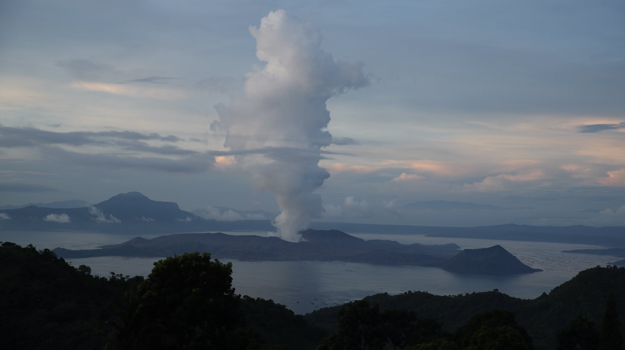 epa09323098 Smoke rises from Taal Volcano as seen from Tagaytay city, Batangas province, Philippines, 05 July 2021. According to the Philippine Institute of Volcanology and Seismology (Phivolcs) latest bulletin on 04 July, the highest level of volcanic sulfur dioxide gas emission was recorded at the Taal volcano and eruption may occur anytime soon. More than 3,000 residents from high-risk villages were evacuated after the volcano started spewing steam, filling the air with toxic gas and prompting health warnings.  EPA/FRANCIS R. MALASIG