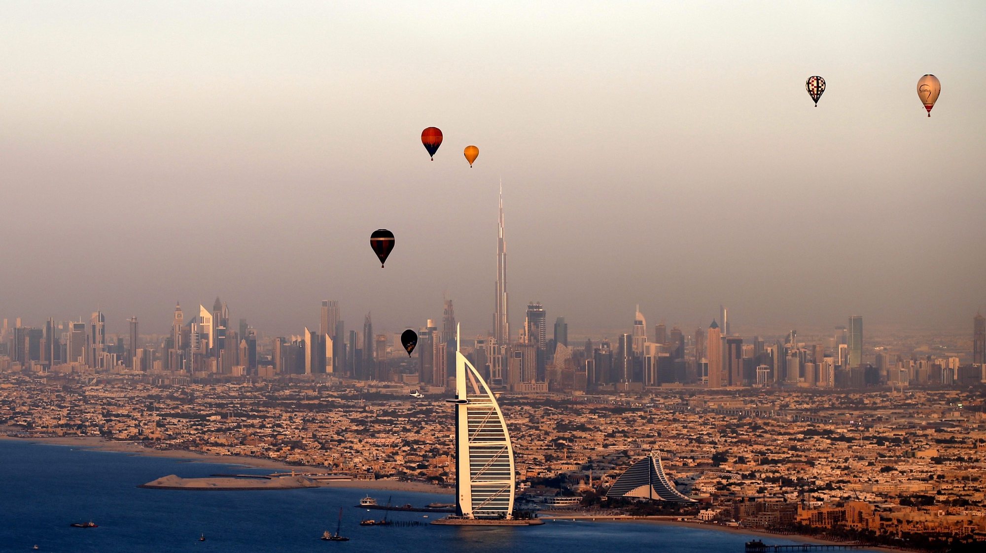 epaselect epa05066387 Hot Air Aerostats fly over the luxury hotel of Burj Al-Arab during Dubai International Balloon Fiesta as part of the last day of Dubai Air Games 2015 in Gulf emirate of Dubai, United Arab Emirates, 12 December 2015.  EPA/ALI HAIDER
