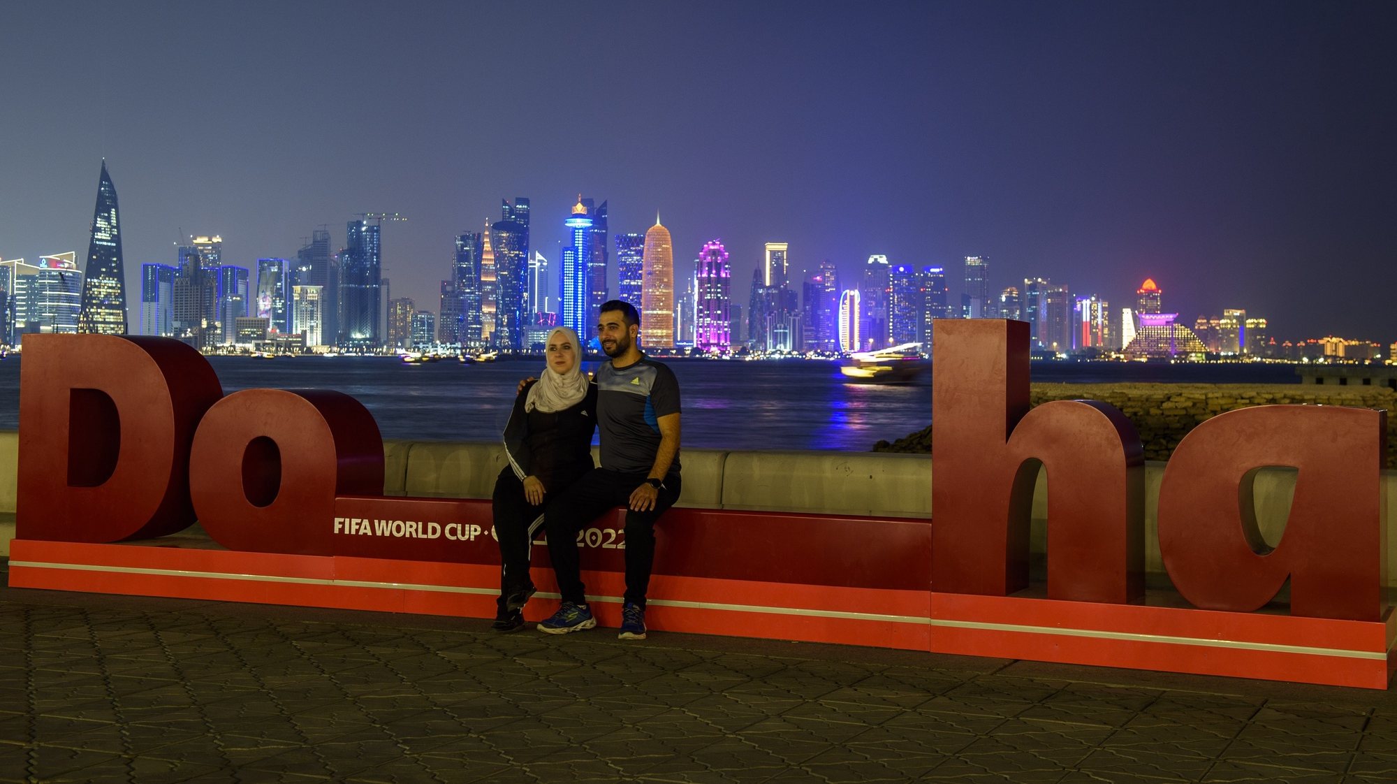 epa10255256 People pose for pictures in front of the skyline of Doha, Qatar, 20 October 2022, 30 days to go until the opening ceremony of the FIFA World Cup Qatar 2022 on 20 November 2022.  EPA/NOUSHAD THEKKAYIL