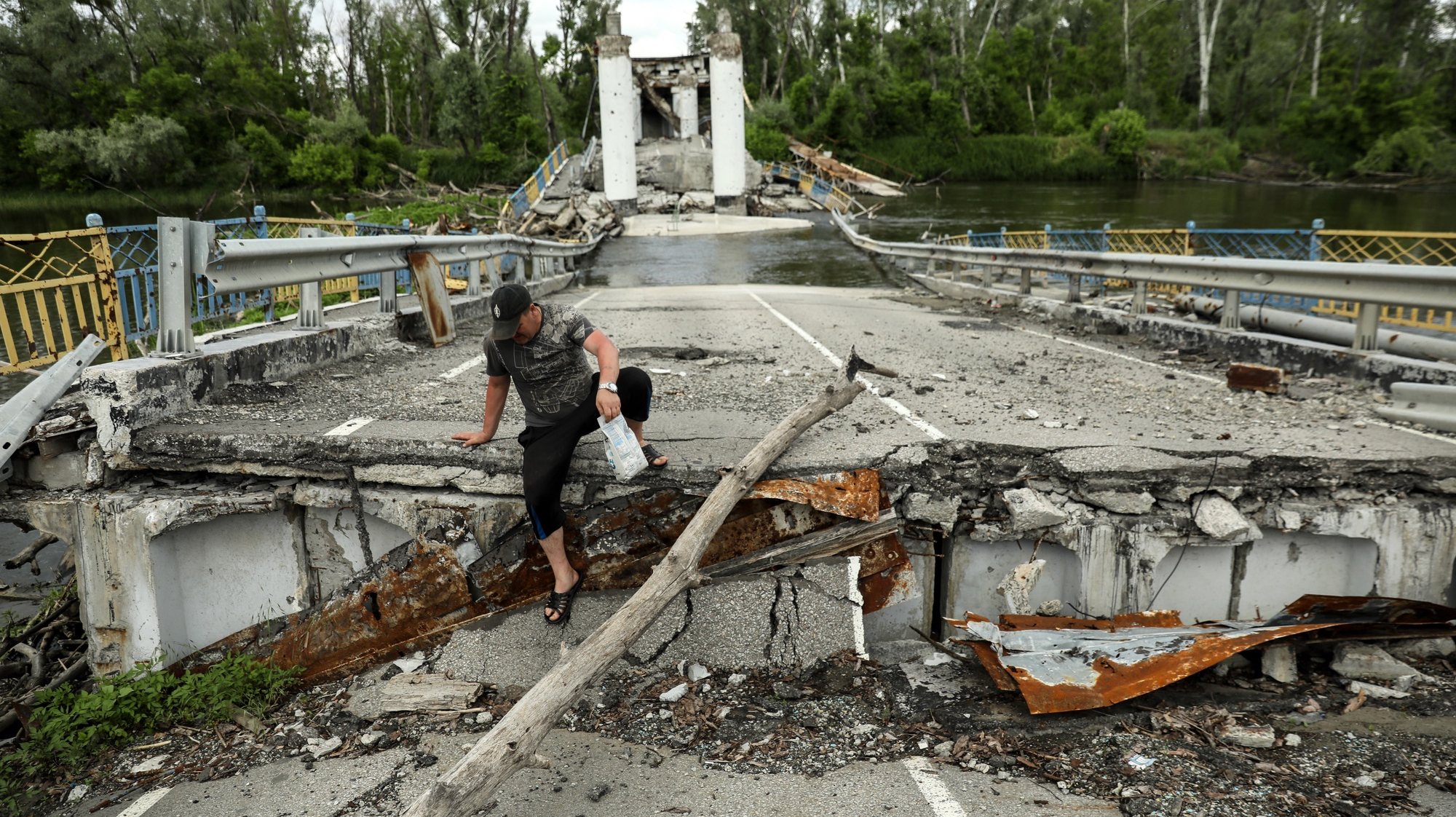 epa10664401 A local resident crosses the Siversky Donets River on a destroyed bridge in Bohorodychne village, Donetsk region, Ukraine, 30 May 2023 (issued 31 May 2023). Before the war, the population of Bohorodyche was around 600 people. Today, only 18 people returned to their homes. Russian troops entered Ukraine on 24 February 2022 starting a conflict that has provoked destruction and a humanitarian crisis.  EPA/OLEG PETRASYUK