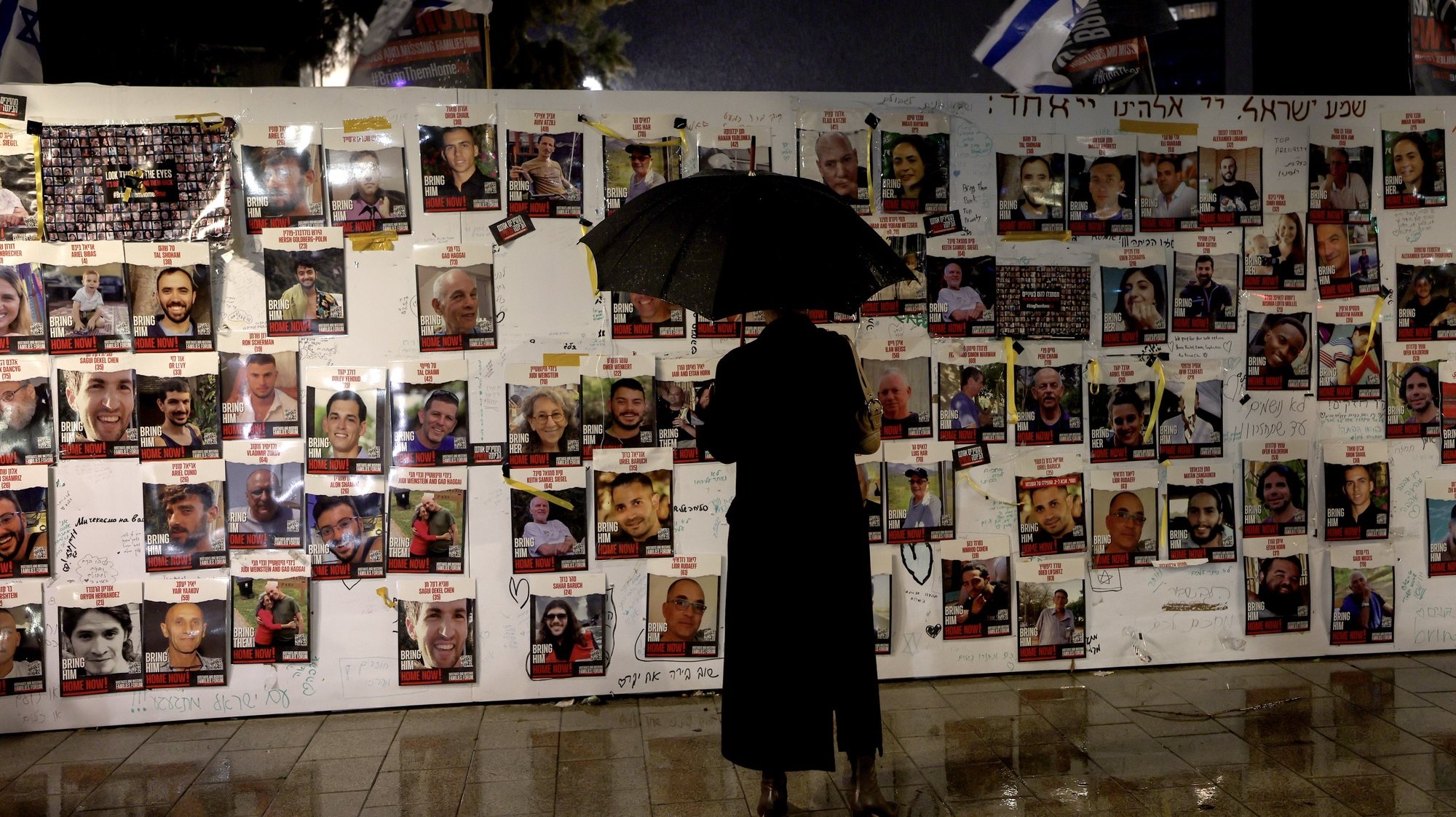 epa11042426 An Israeli activist looks at pictures of hostages held by Hamas in Gaza Strip, at the Hostages Square, in Tel Aviv, Israel, 23 December 2023. Thousands of Israelis and Palestinians have died since the militant group Hamas launched an unprecedented attack on Israel from the Gaza Strip on 07 October, and the Israeli strikes on the Palestinian enclave which followed it.  EPA/ATEF SAFADI