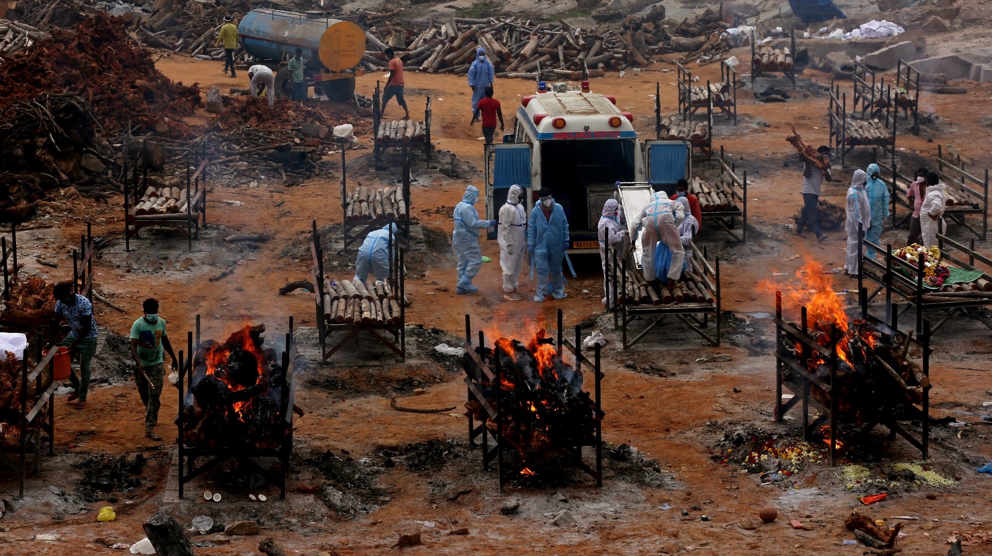 epaselect epa09175681 Funeral pyres for COVID-19 victims burn during a mass funeral at a makeshift cremation ground at Giddenahalli in the outskirts of Bangalore, India, 03 May 2021. India recorded a massive surge of 368,147 fresh Covid-19 cases and 3,455 deaths in the last 24 hours.  EPA/JAGADEESH NV