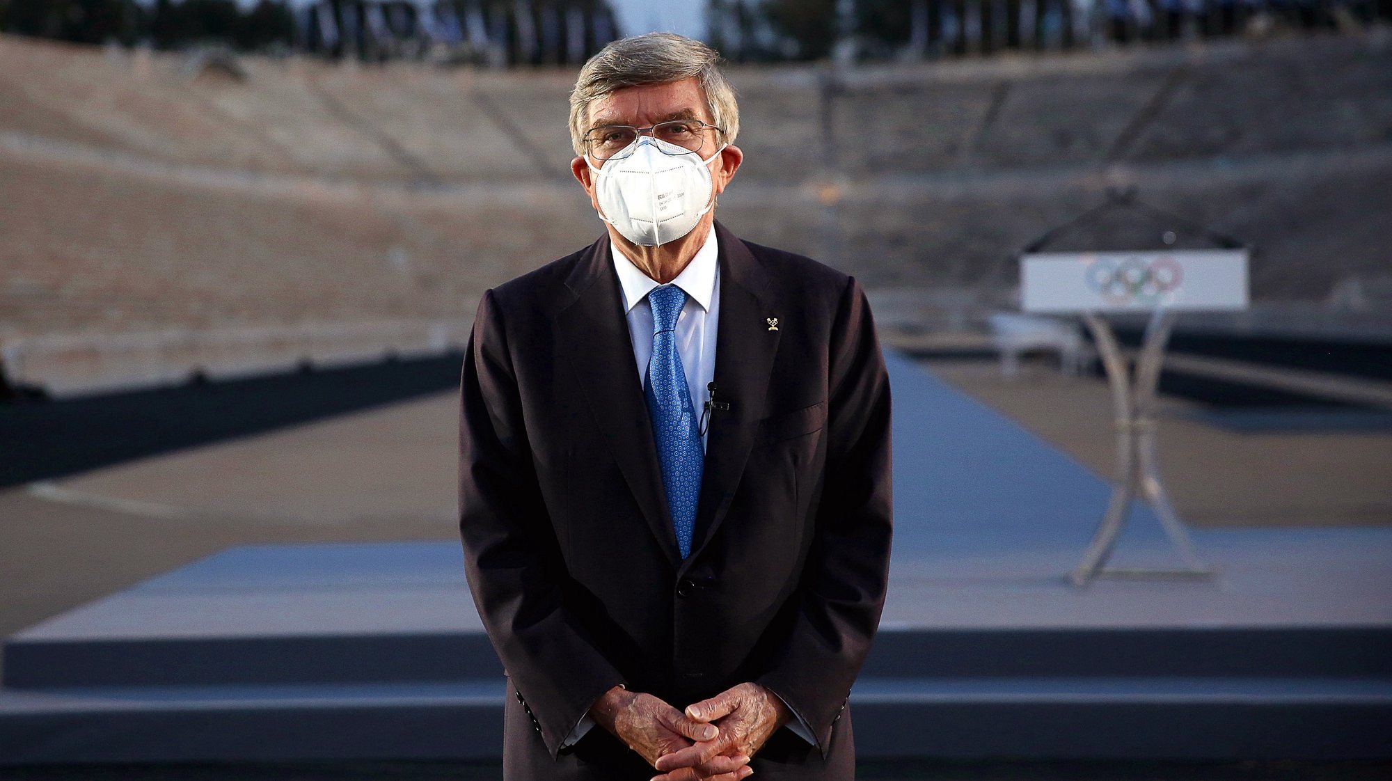 epa09105362 International Olympic Committee (IOC) president Thomas Bach of Germany wearing a protective face mask stands in the Panathenaic Stadium, venue of the first modern Olympic Games in 1896, in Athens, Greece, 29 March 2021. Bach visits Athens to attend the ceremony for the inauguration of the new lighting of the Panathenaic Stadium.  EPA/ORESTIS PANAGIOTOU