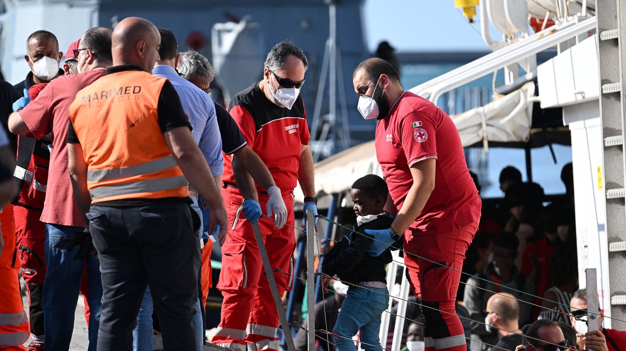 epa10710616 A member of the Italian Red Cross assists a migrant child arriving on the ship of the NGO Salvamento Maritimo Humanitario after docking in the port of Salerno, Italy, 25 June 2023. A group of 172 migrants, among them 55 unaccompanied minors, from the sub-Saharan area arrived in the port in good health and tested negative for Covid.  EPA/MASSIMO PICA