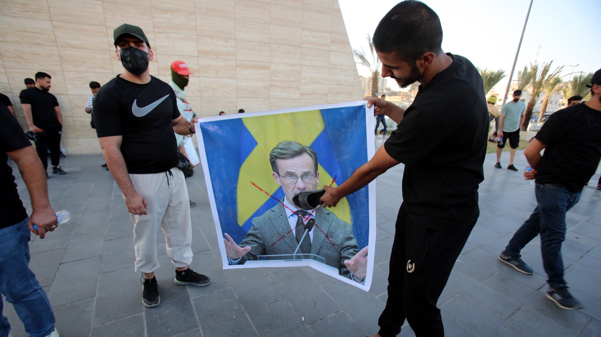 epa10758782 Iraqi demonstrators carry a crossed out picture of the Swedish prime minister during a protest at Tahrir square in Baghdad, Iraq, 20 July 2023. Dozens of supporters of Iraqi Shiite Popular Mobilization Forces gathered in Baghdad over the planned burning of a copy of the Koran in front of the Iraqi embassy in Stockholm for the second time.  EPA/AHMED JALIL