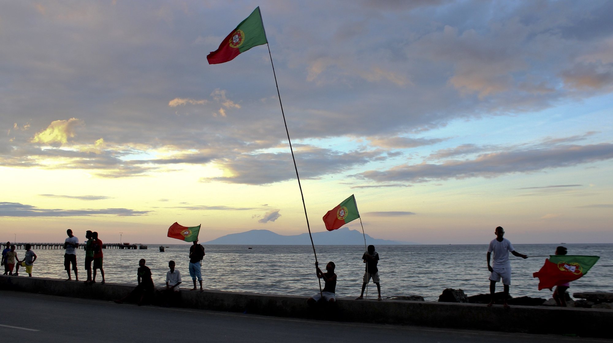 Timorenses empunham bandeiras de Portugal, no dia em que a seleção nacional de futebol portuguesa se estreia no Mundial2014 de futebol, no jogo do Grupo G contra a Alemanha, em Díli, Timor-Leste, 16 de junho de 2014. (ACOMPANHA TEXTO). ANTÓNIO AMARAL/LUSA