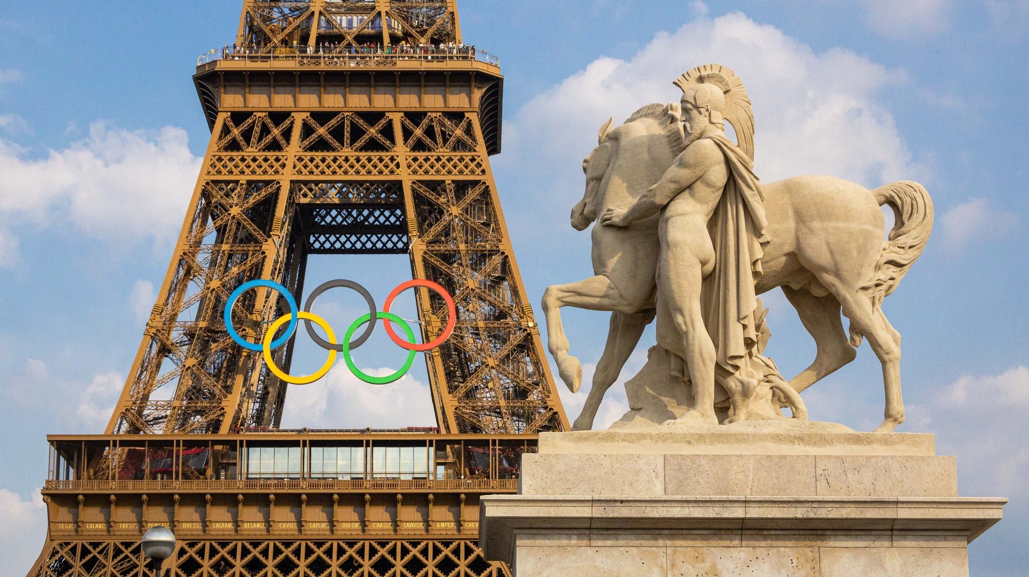 epa11439905 The Eiffel tower decorated with the Olympic rings seen from the working site of the opening ceremony at the Trocadero in Paris, France, 26 June 2024. The opening ceremony of the Paris 2024 Olympic Games will begin with a nautical parade on the Seine and ends on the protocol stage in front of the Eiffel Tower on 26 July 2024.  EPA/CHRISTOPHE PETIT TESSON